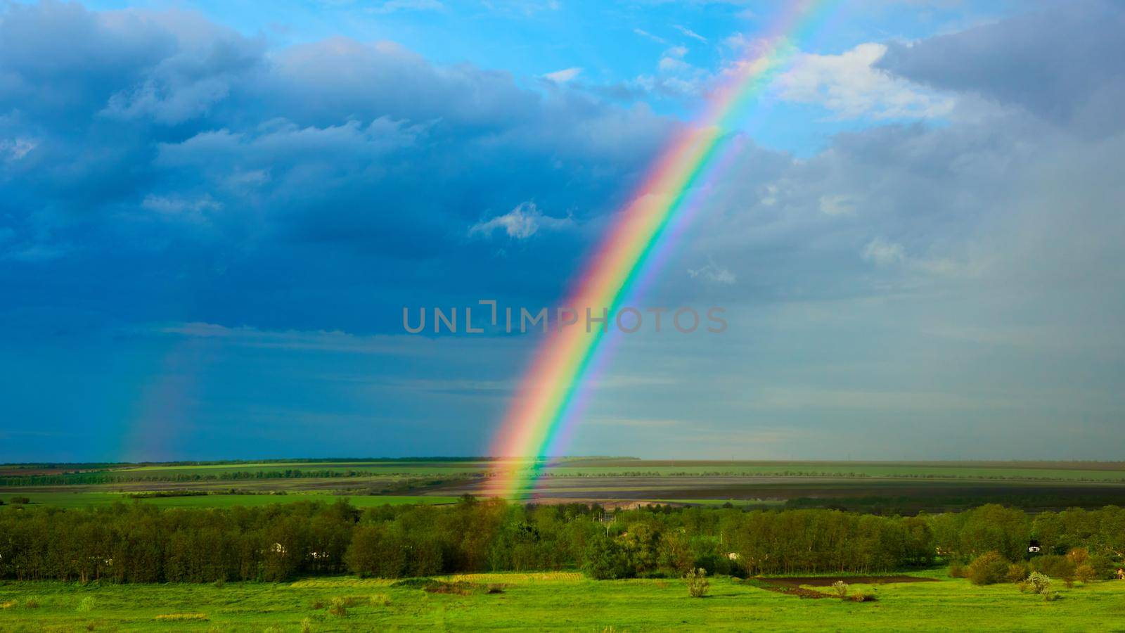 The Rainbow over a field after thunderstorm by sarymsakov