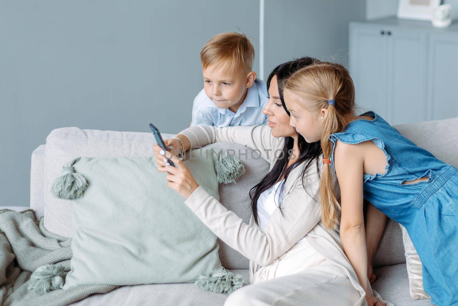 mom with two kids watching videos on her smartphone. photo with a copy -space.