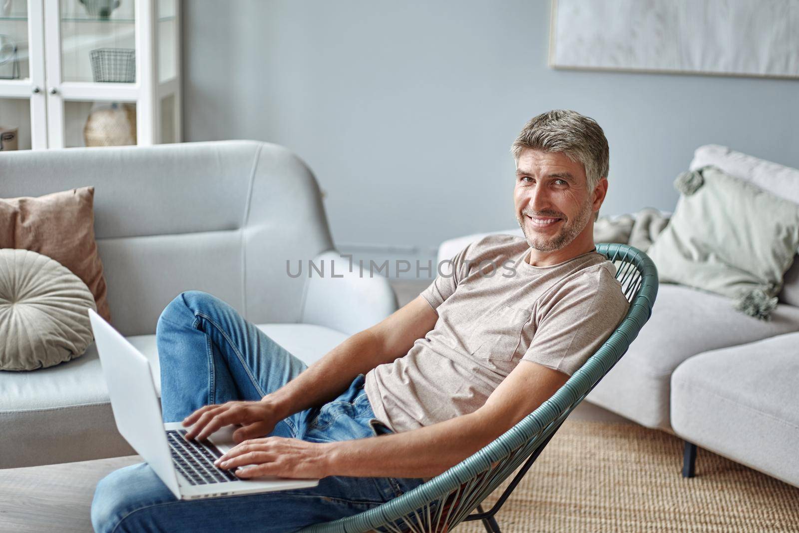 young man with a laptop sitting in a cozy armchair . side view.