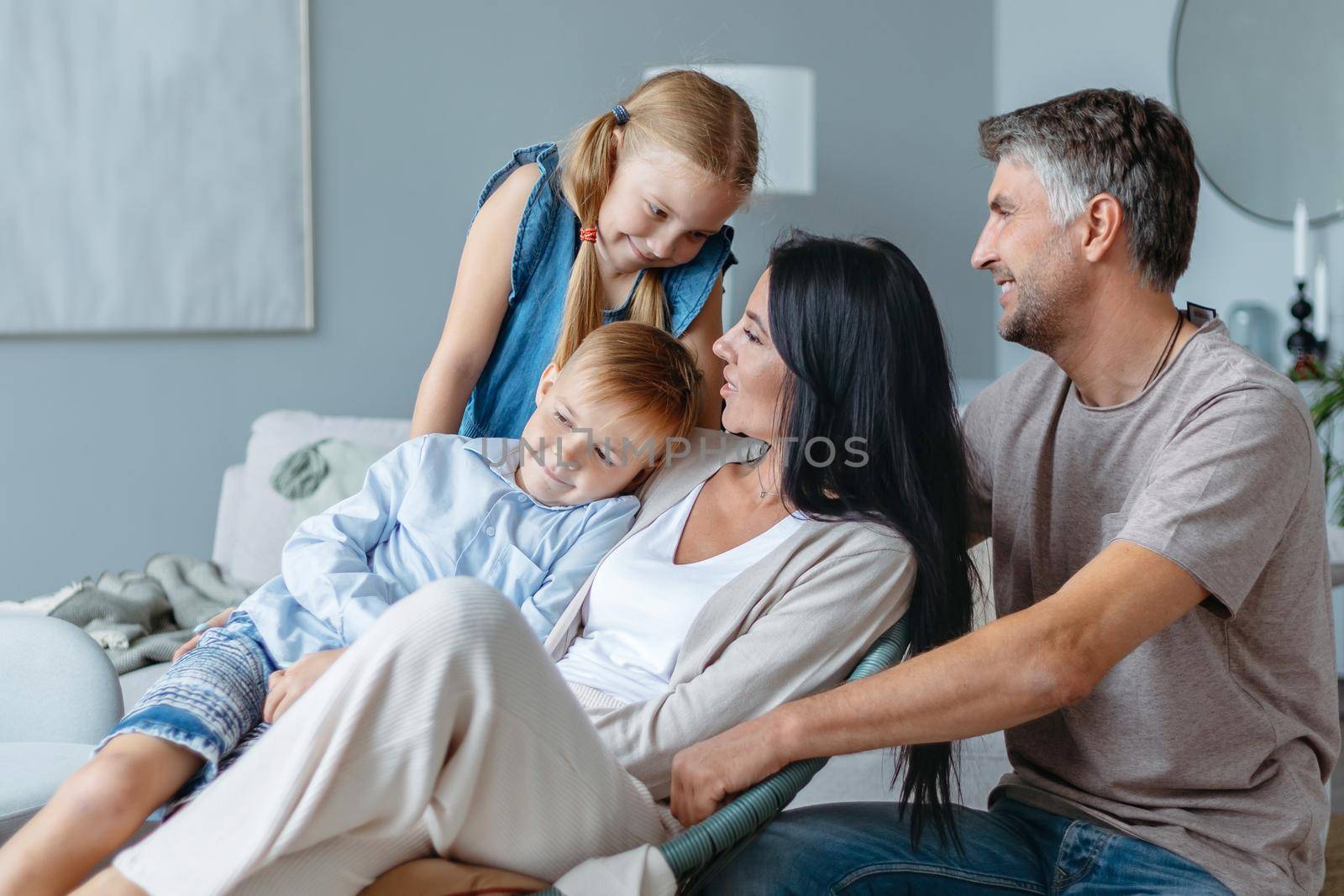 family with two children communicates in a cozy living room . by SmartPhotoLab