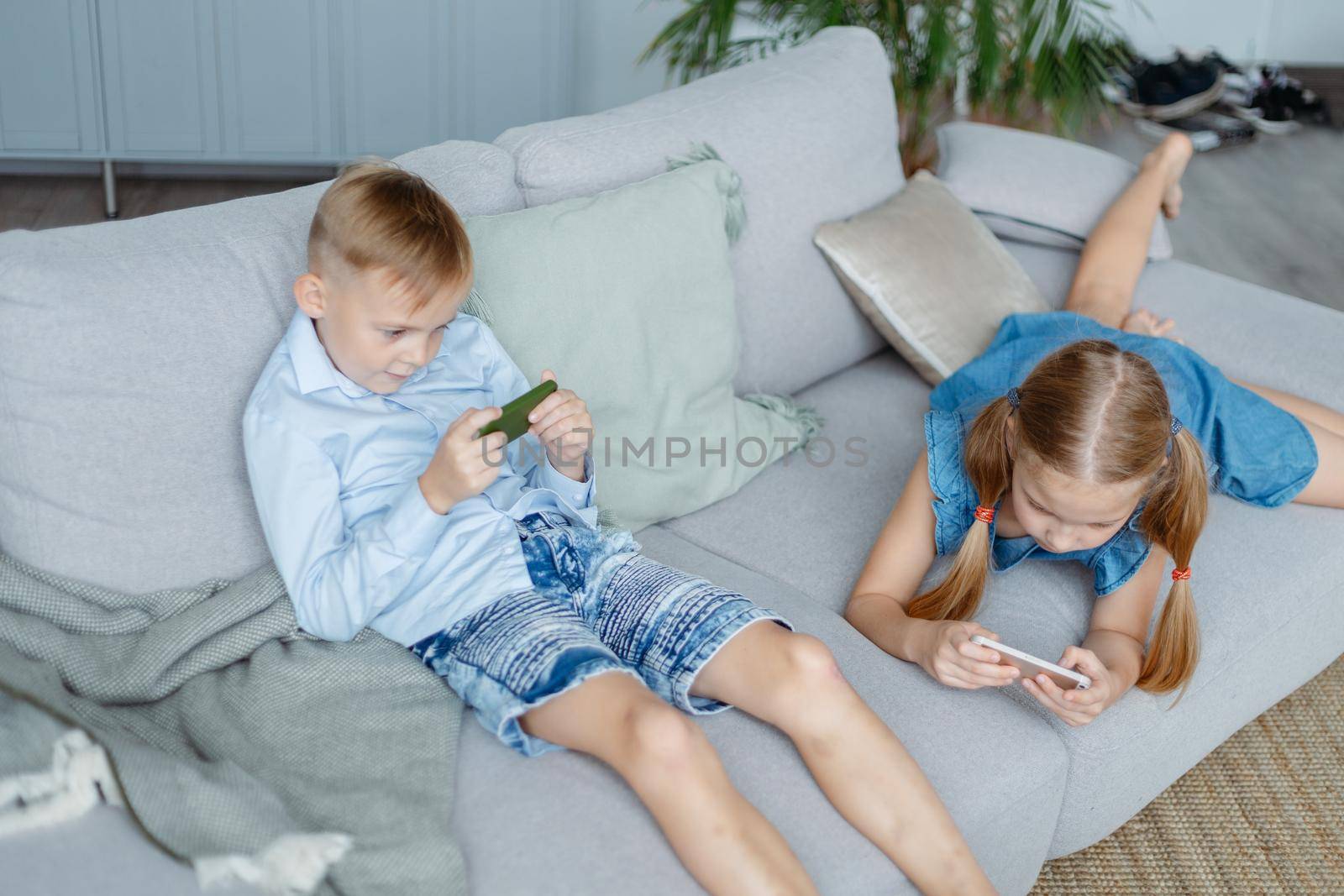 little brother and sister using their smartphones in their free time. by SmartPhotoLab