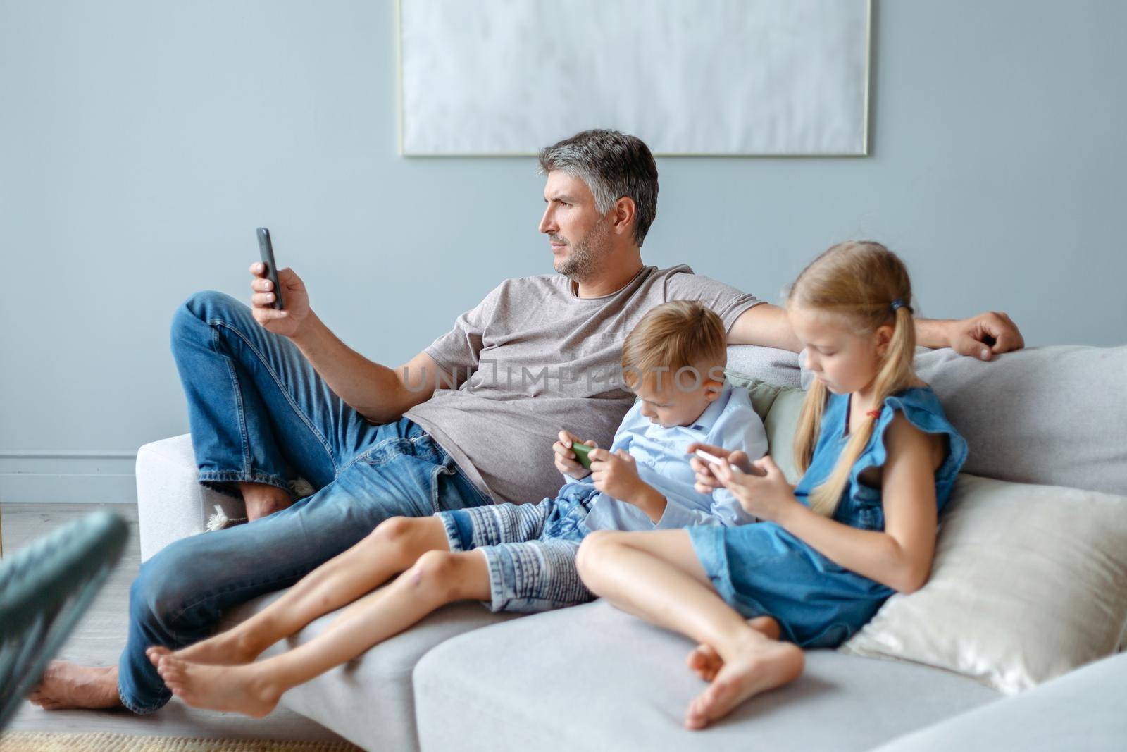 father and two children using their smartphones in their free time. Family staying at home.