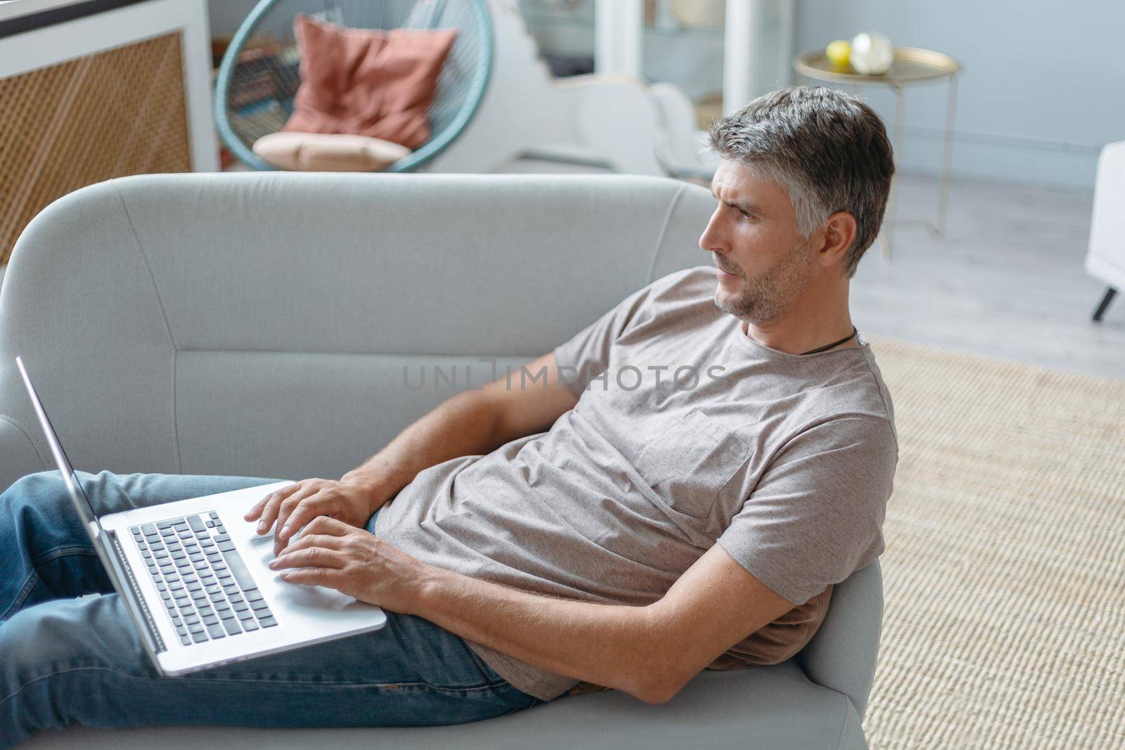man with a laptop is resting in his living room. side view.