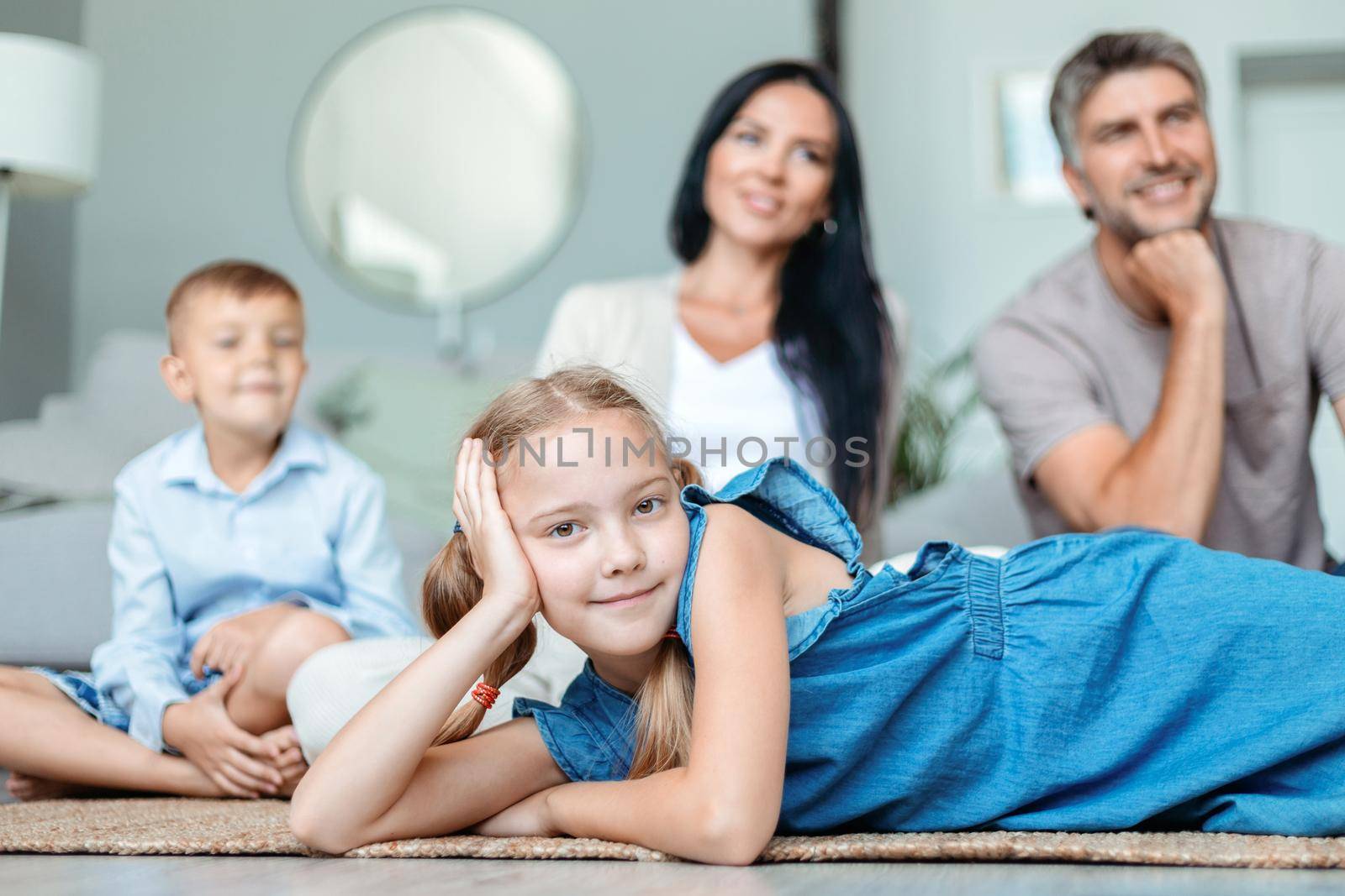 little girl lying on the floor in front of her family. photo with a copy space.