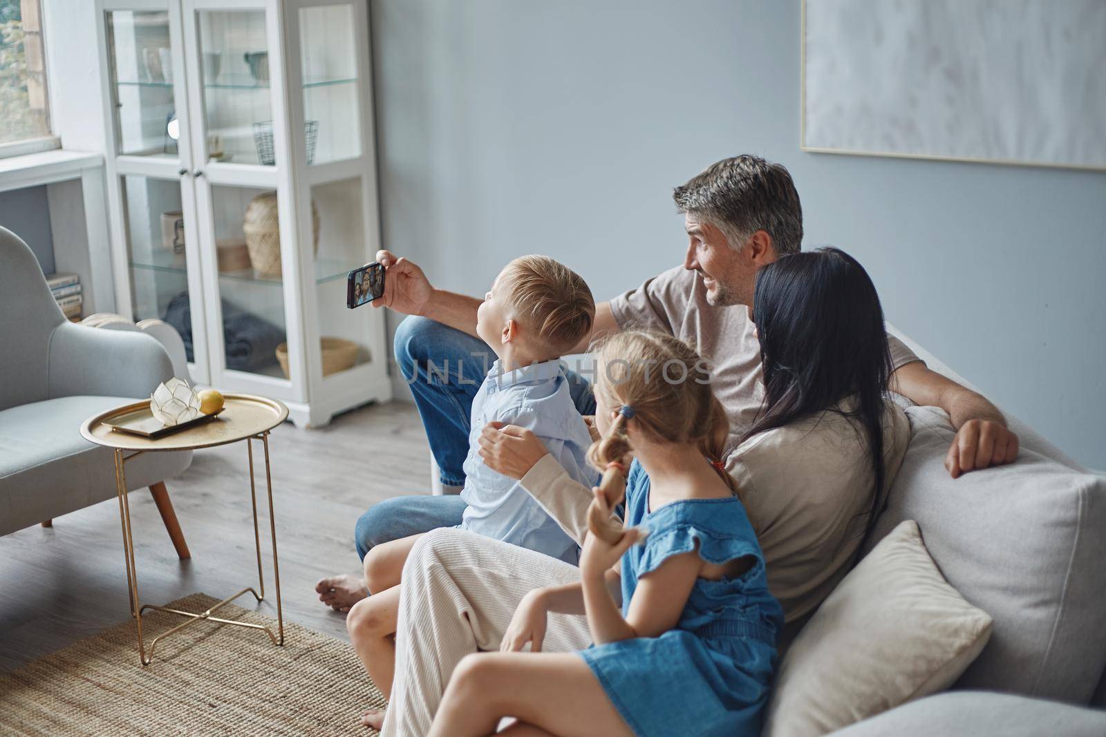 happy man and his family taking a selfie in their apartment. by SmartPhotoLab