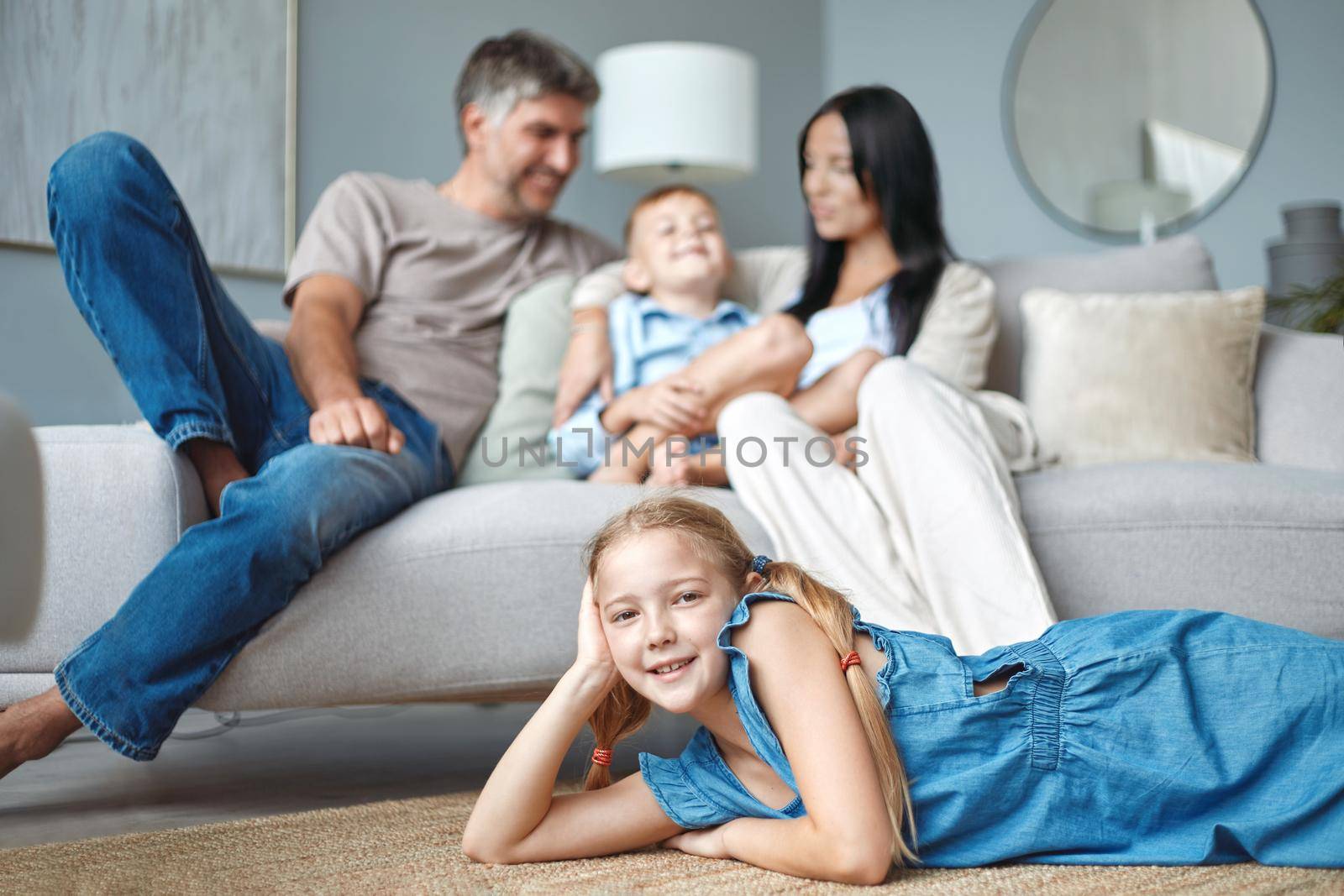 Cute little girl lying on the floor and smiling at camera. Family staying at home.