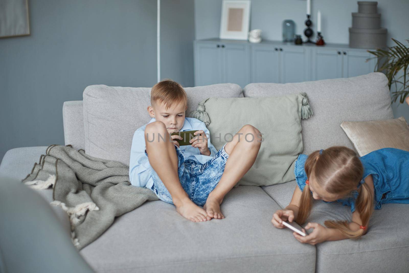 little brother and sister using their smartphones in their free time. by SmartPhotoLab