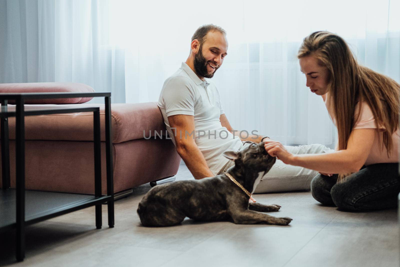 Cheerful Woman and Man Having Fun Time with Pet French Bulldog at Home by Romvy