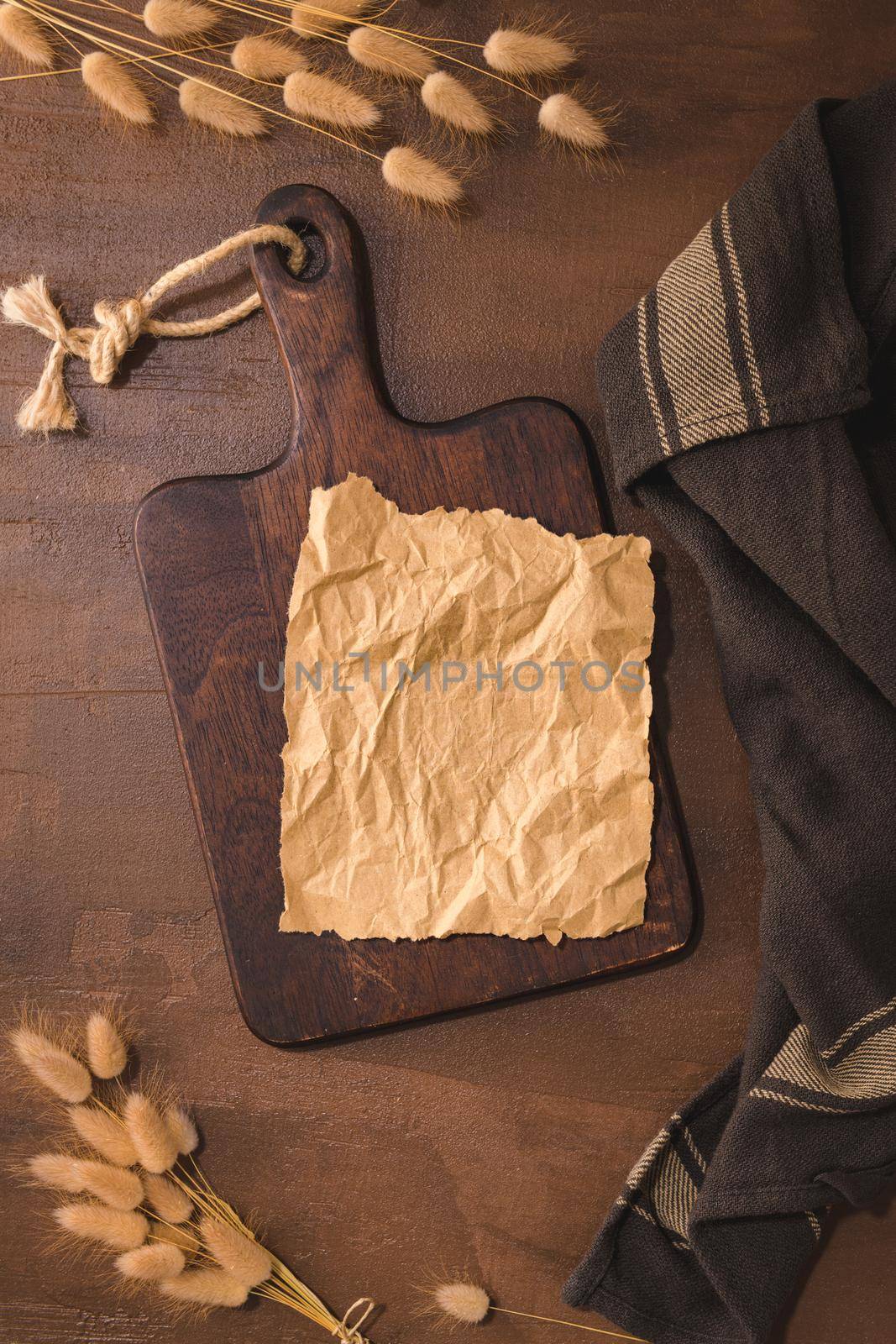 Crumpled paper and wooden cutting board on brown moody and rustic kitchen countertop.