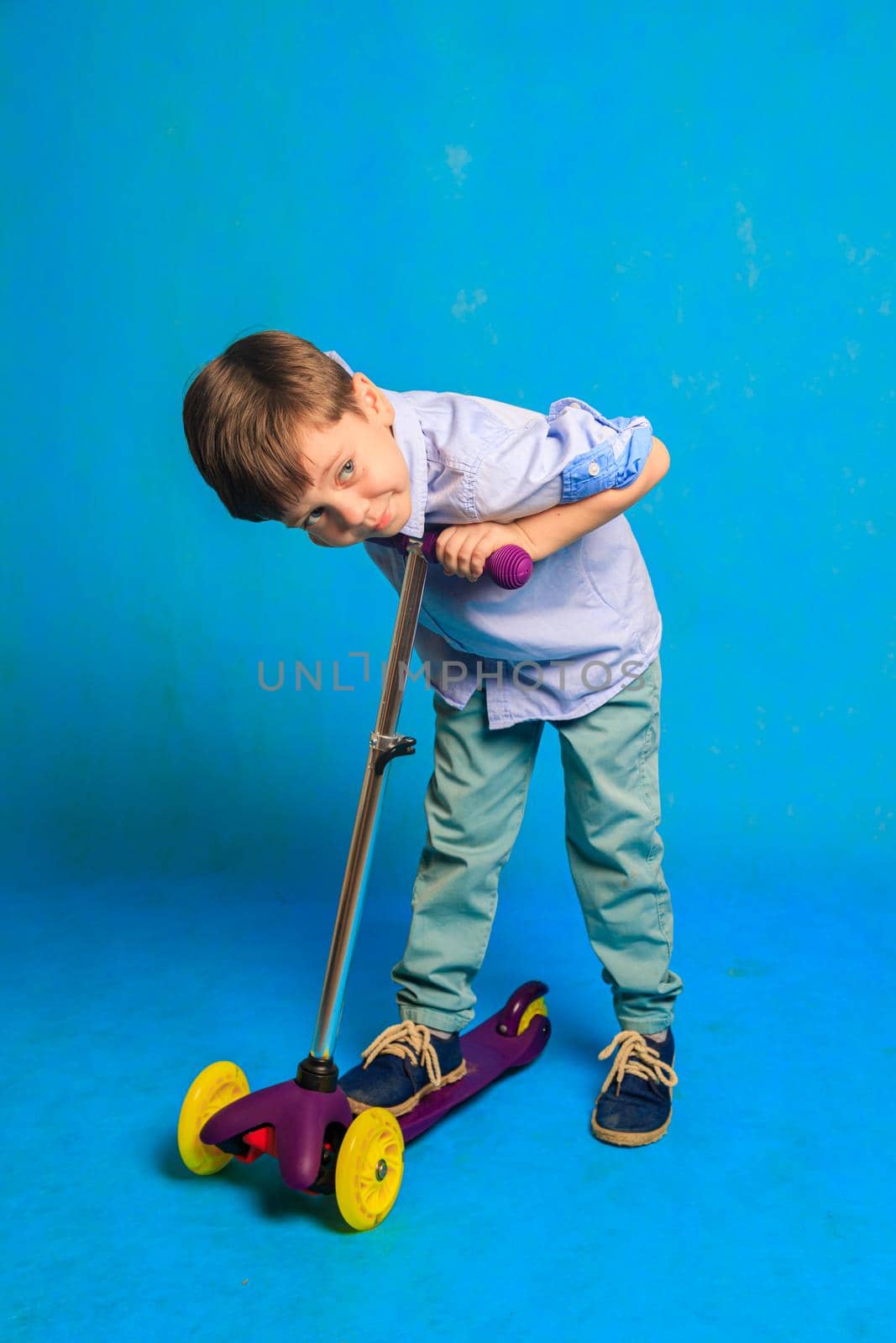 A boy on a scooter on a blue background . An article about children's scooters. An article about the choice of a scooter for a child. A happy child. Blue background and a boy. by alenka2194