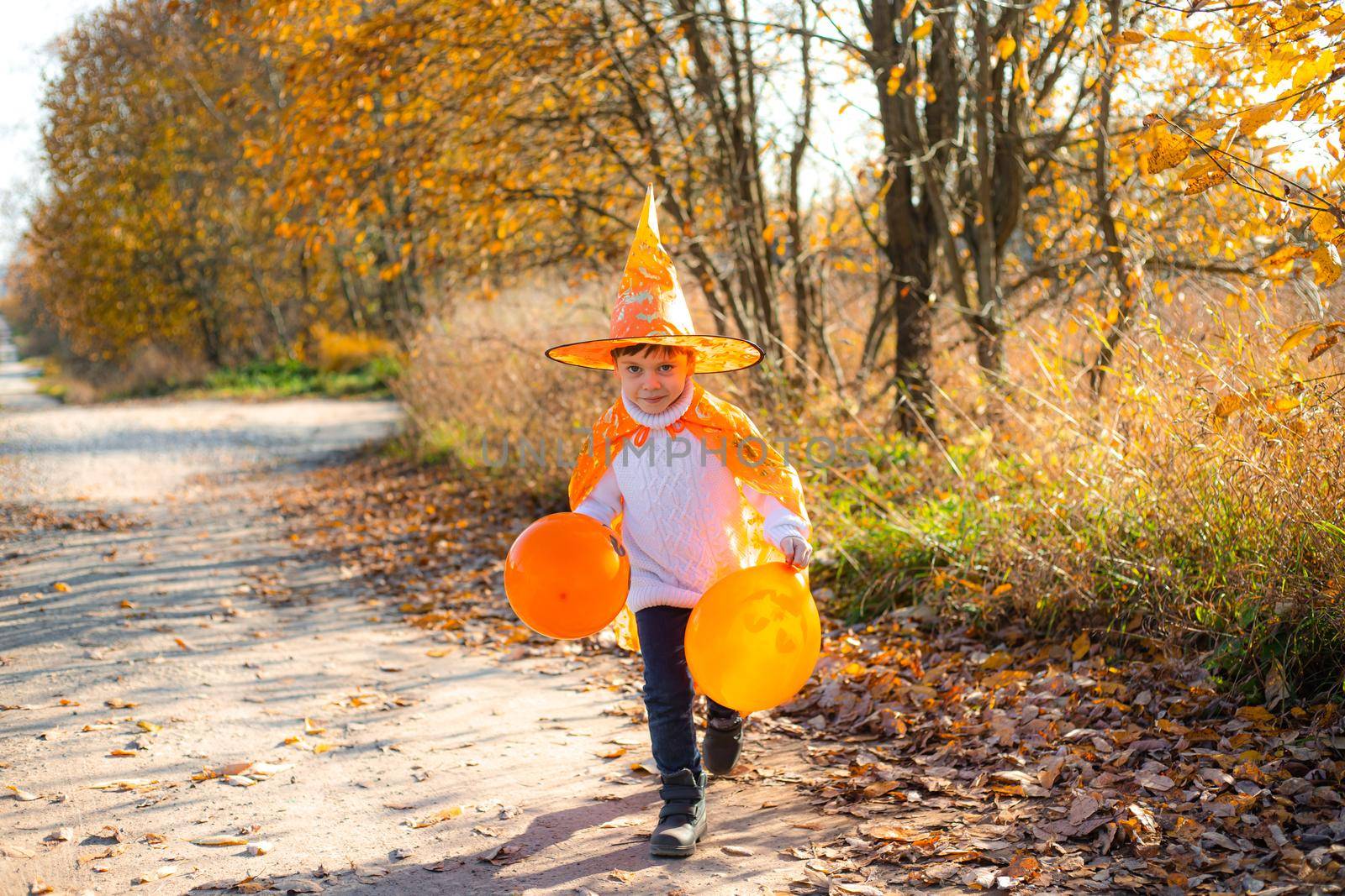 Portrait of a boy in Halloween clothes with pumpkin balloons on the street . A traditional holiday. October 31. Autumn Holiday