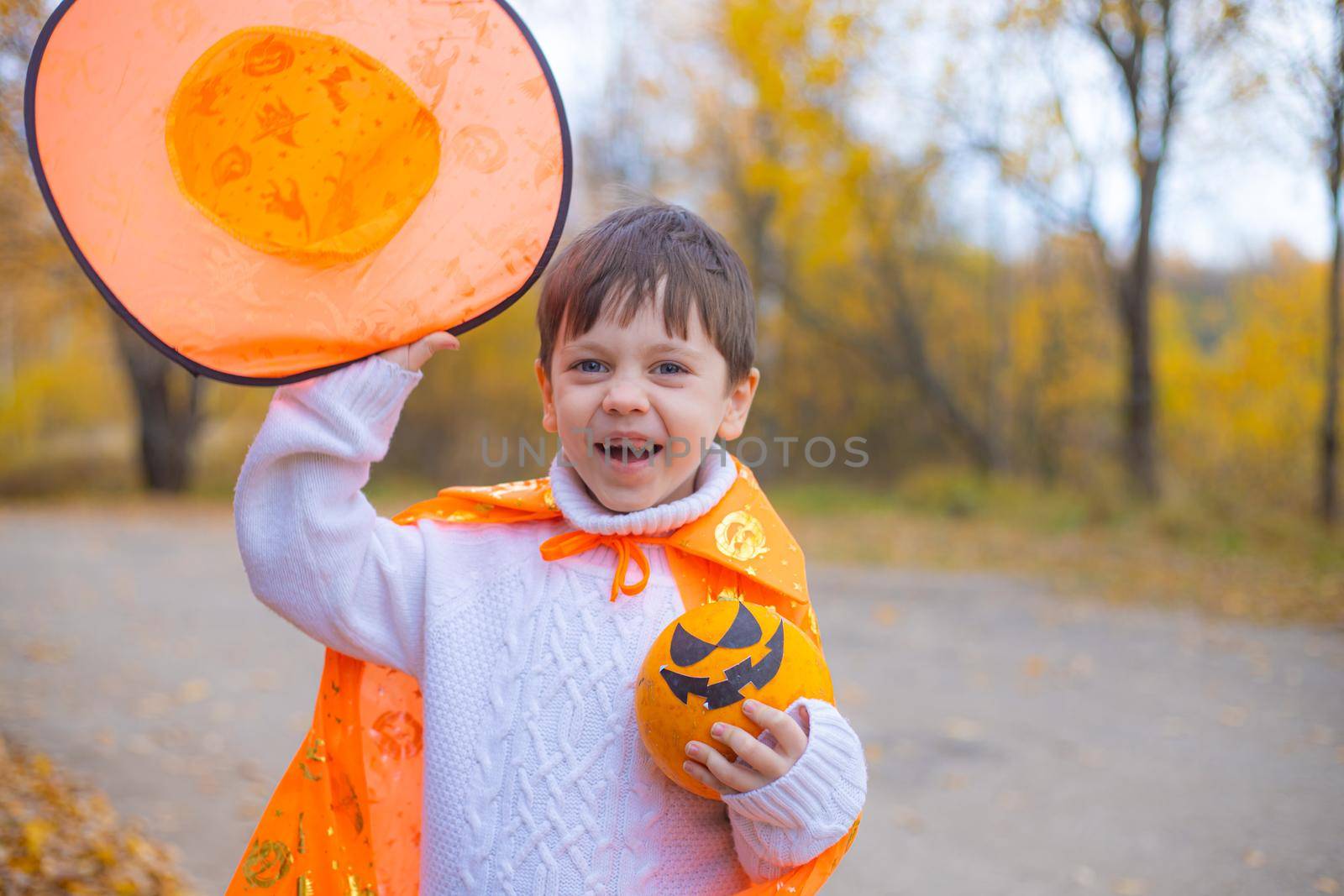 Portrait of a boy in Halloween clothes with a pumpkin on the street . A traditional holiday. October 31. by alenka2194