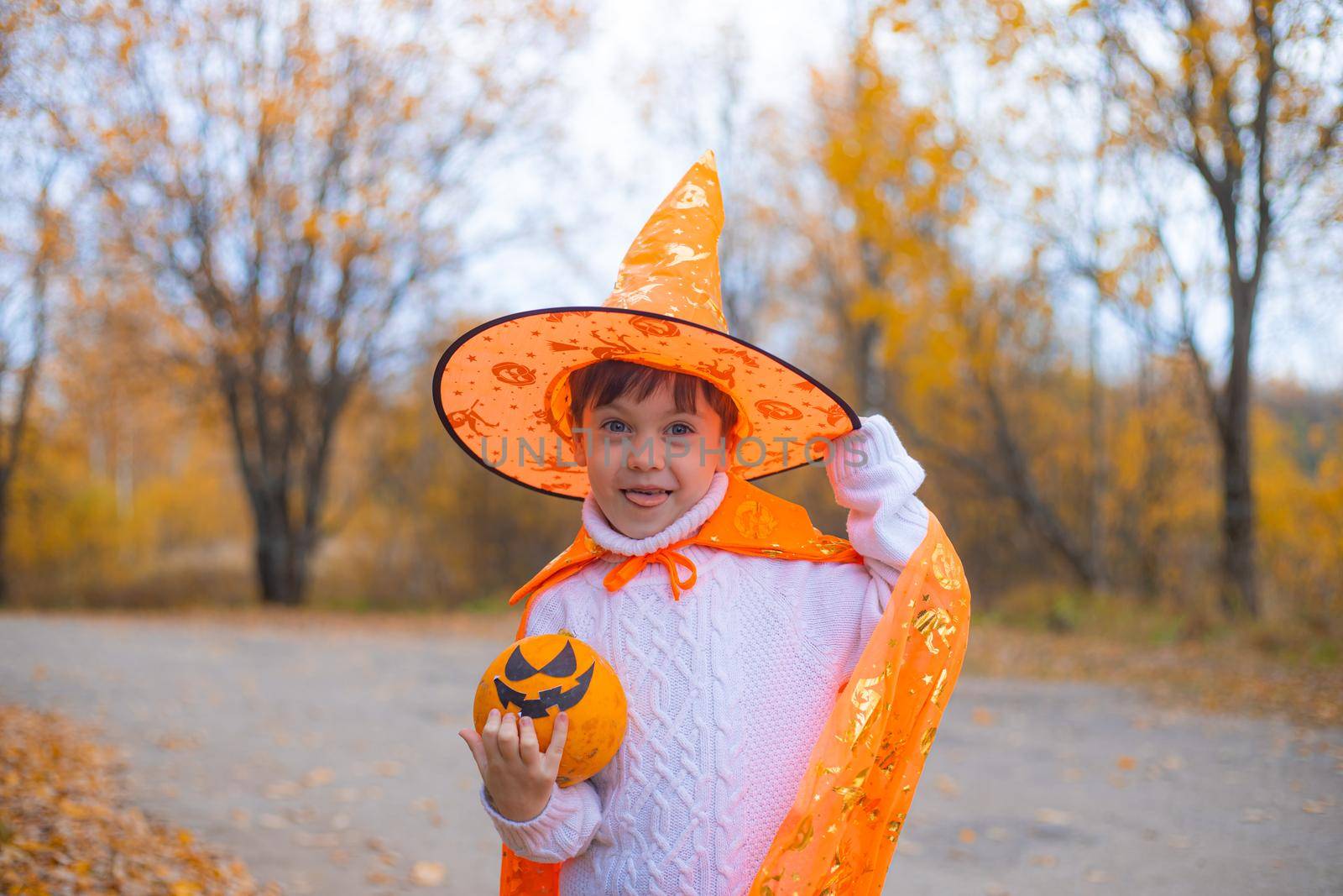 Portrait of a boy in Halloween clothes with a pumpkin on the street . A traditional holiday. October 31. Autumn Holiday