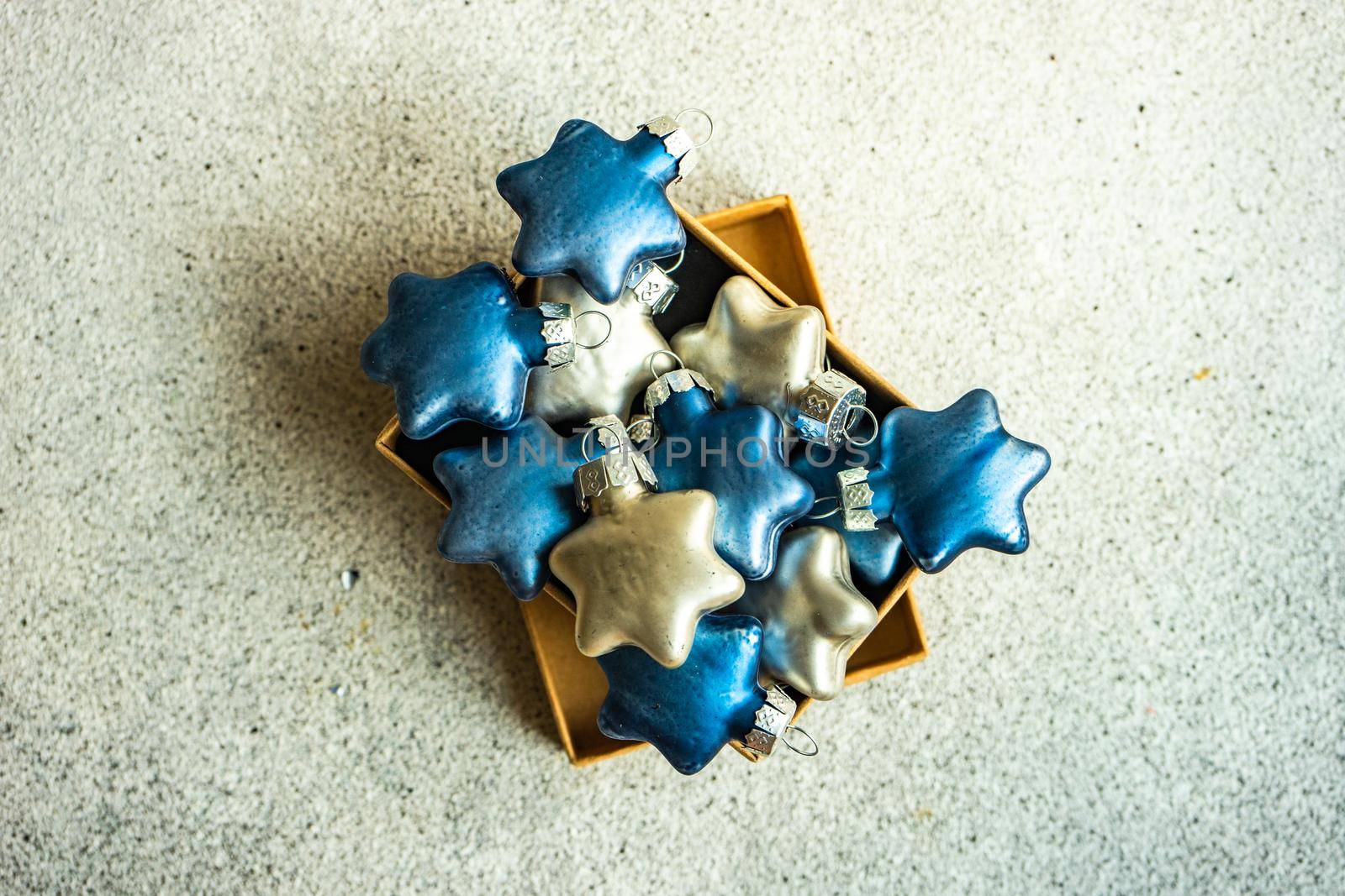 Rustic gift box with blue and silver star shaped balls on concrete background