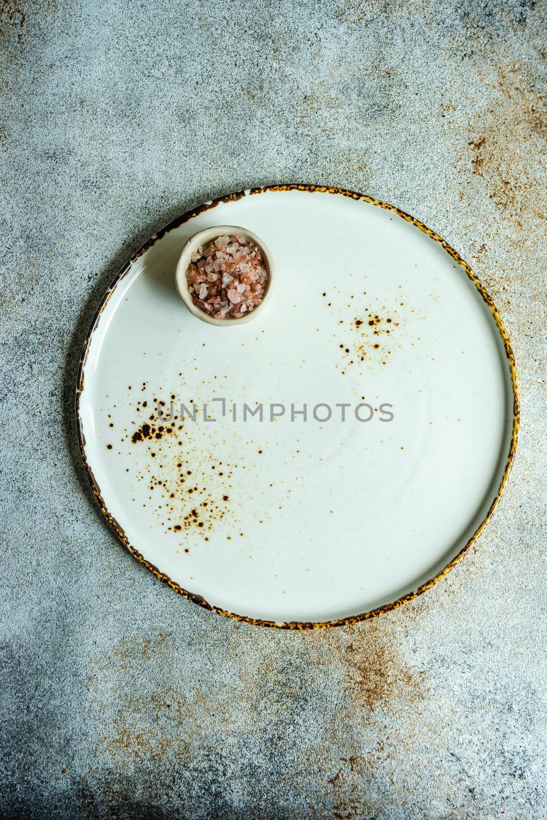Ceramic plate and bowl with pink salt on concrete table