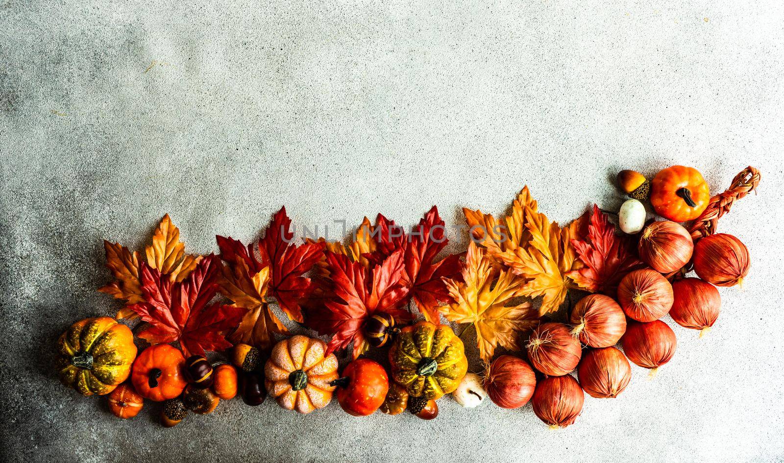 Fake maple leaves on the concrete background by Elet