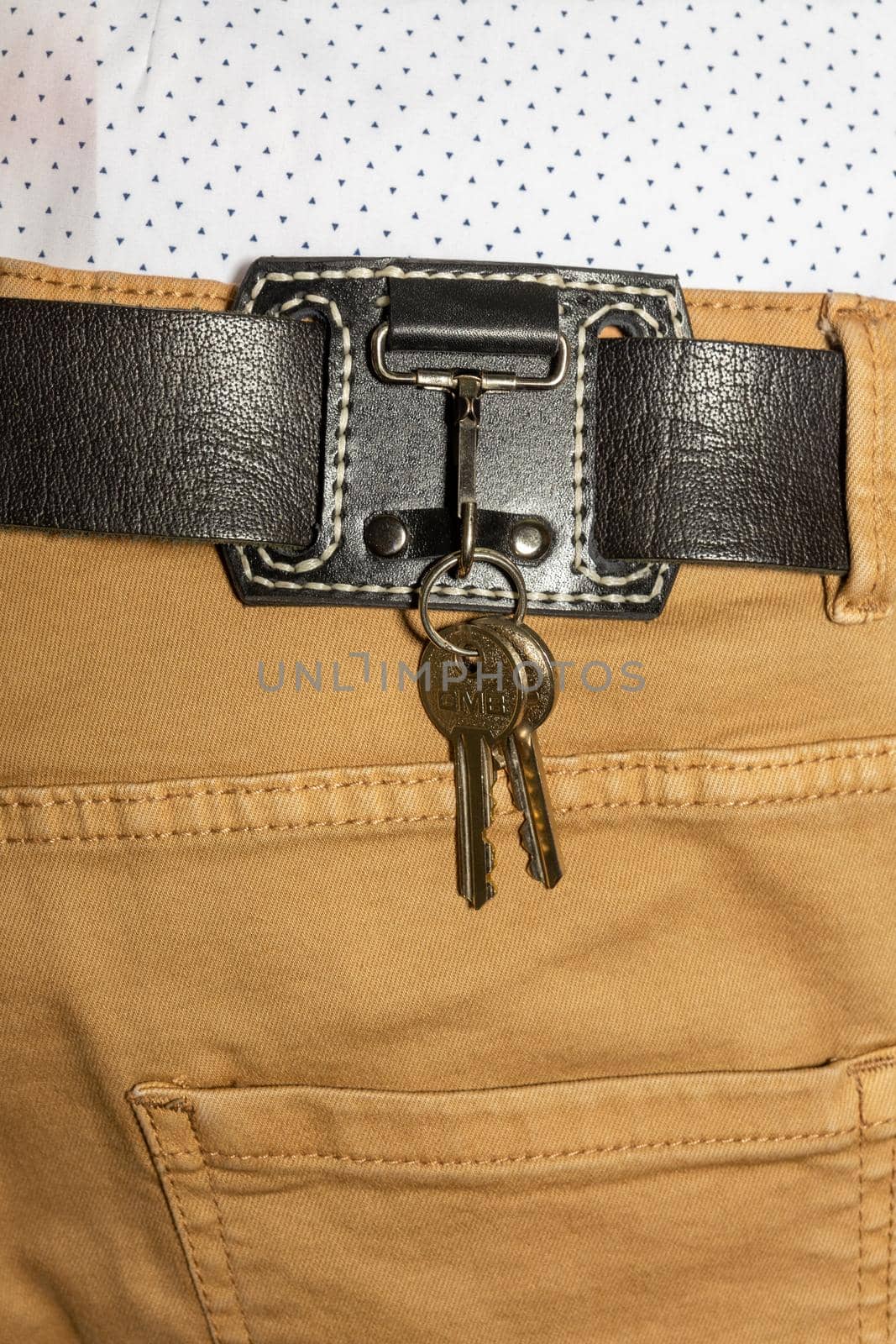 leather key strap with iron carabiner with two keys mounted on a leather belt.