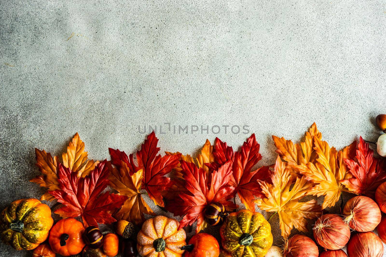 Frame made with fake autumnl leaves and harvest vegetables on the concrete background