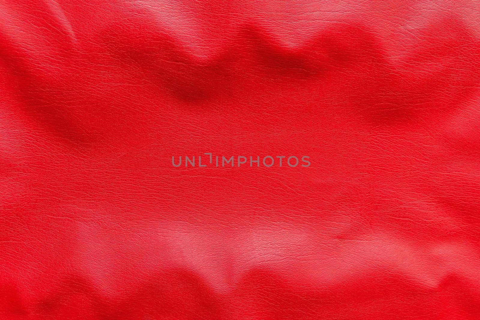 Wavy texture of red faux leather background, close-up.