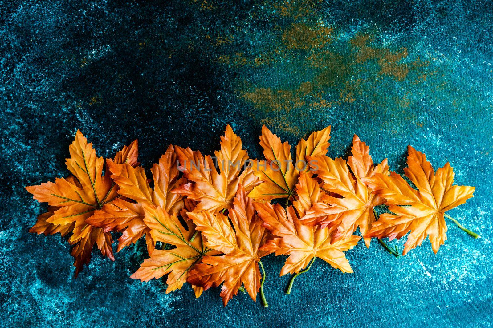 Bright red and yellow fake maple leaves on the concrete background