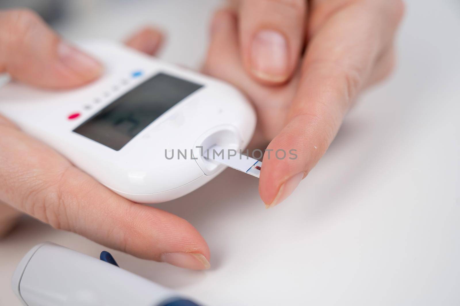 Woman measures blood sugar level with a glucometer