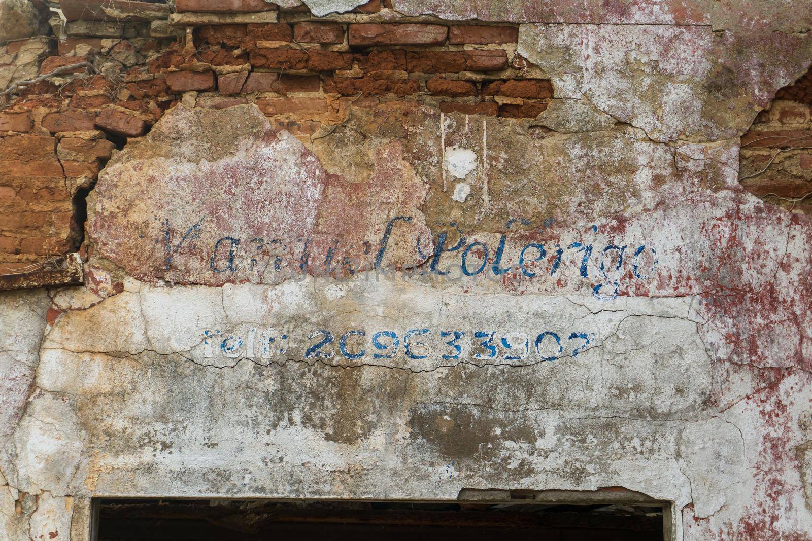 Erased handwritten inscription over the entrance to the ruined building close up background