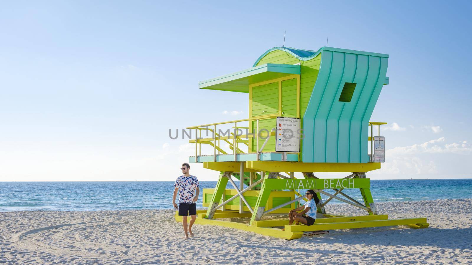 Miami Beach, a couple on the beach at Miami Florida, lifeguard hut Miami Asian women and caucasian men on the beach during sunset. man and woman watching sunrise