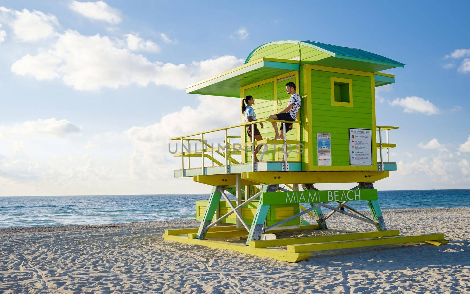 Miami Beach, a couple on the beach at Miami Florida, lifeguard hut Miami Asian women and caucasian men on the beach during sunset. man and woman watching sunrise