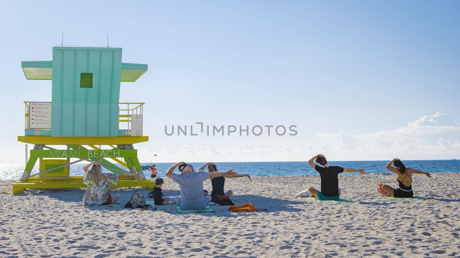 group of people doing yoga during sunrise on the beach at Miami Florida South Beach. people doing yoga in the morning