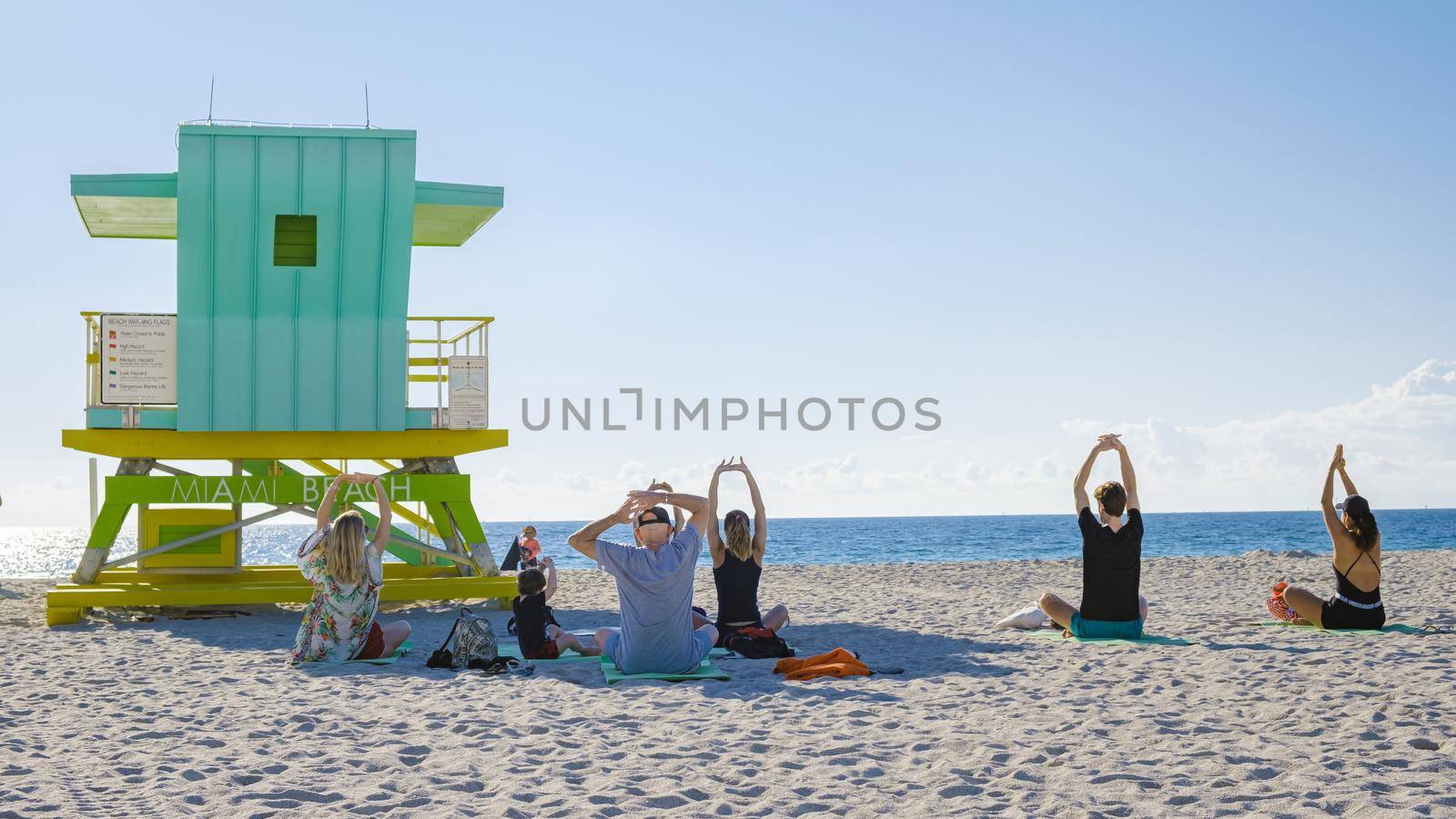 group of people doing yoga during sunrise on the beach at Miami Florida South Beach. people doing yoga in the morning