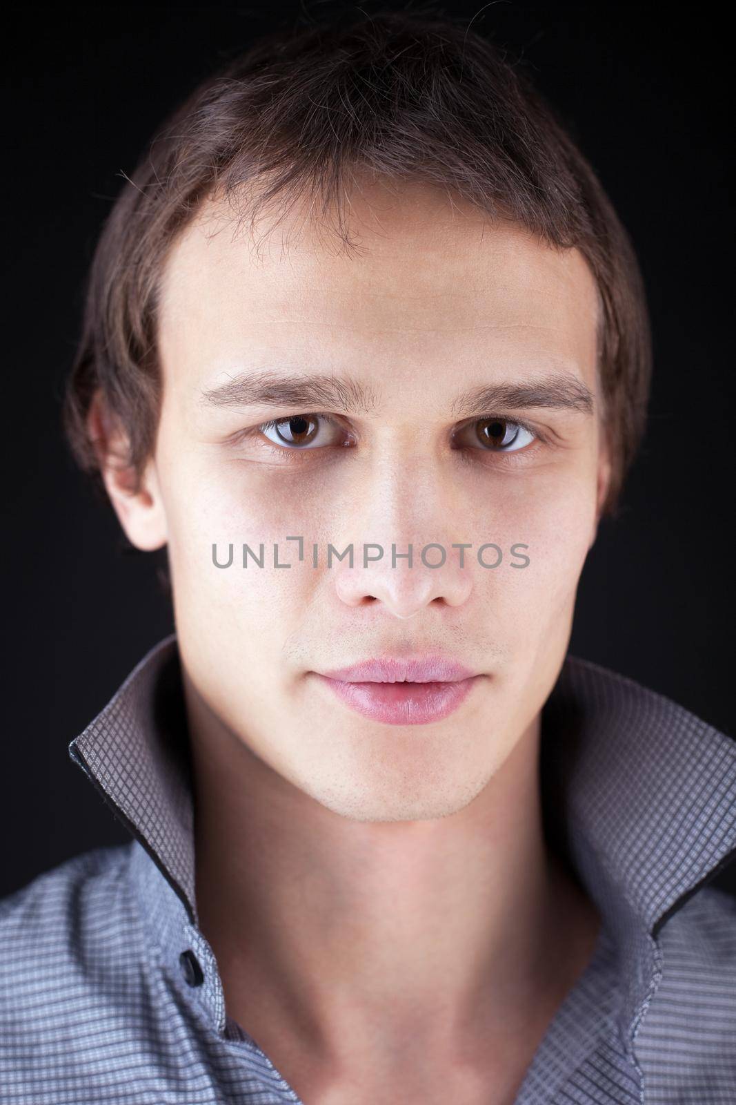 Serious young man close-up portrait in dark
