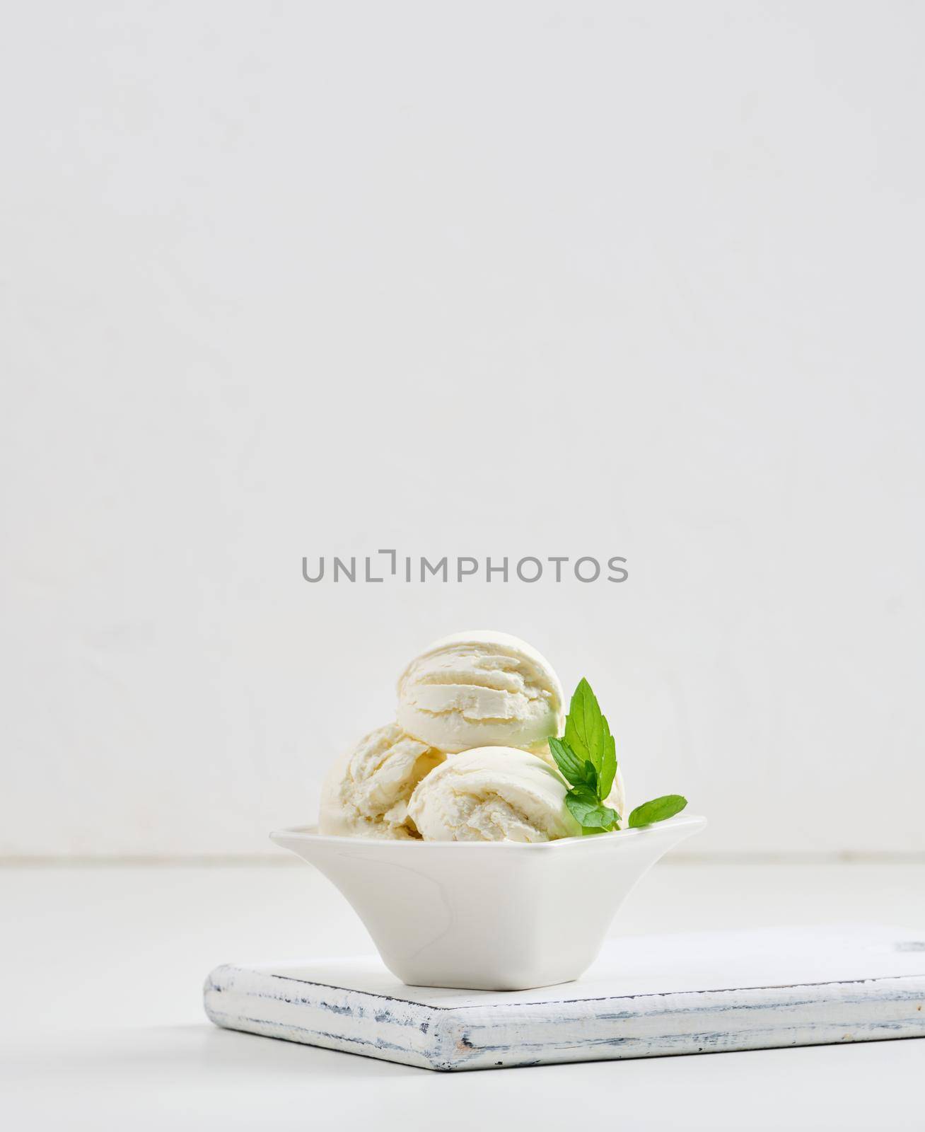 Vanilla ice cream balls with green mint leaf in a white ceramic plate