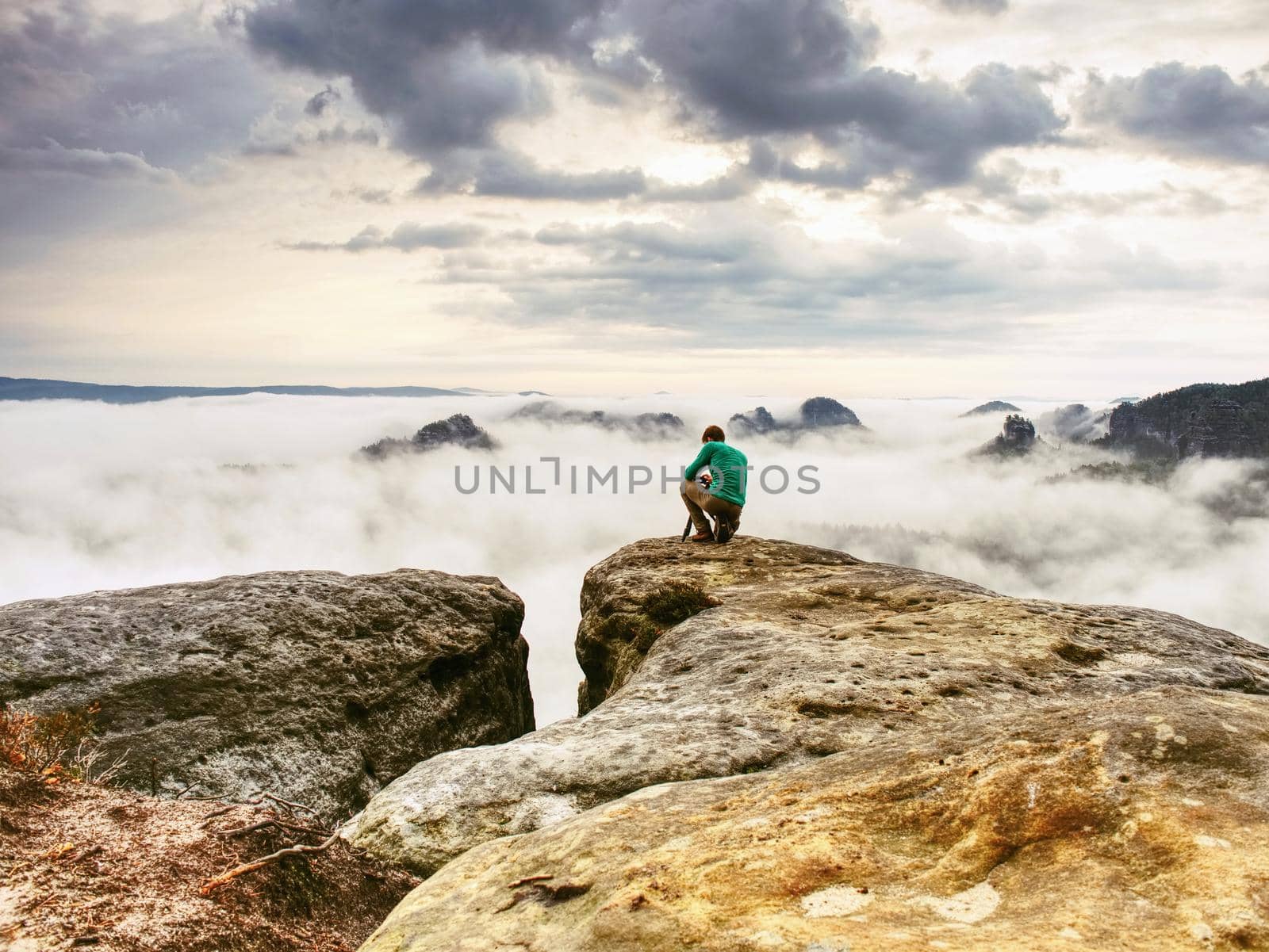 Photographer looks into fall landscape through camera viewfinder. Man prepare camera to takes impressive photos of misty fall mountains.