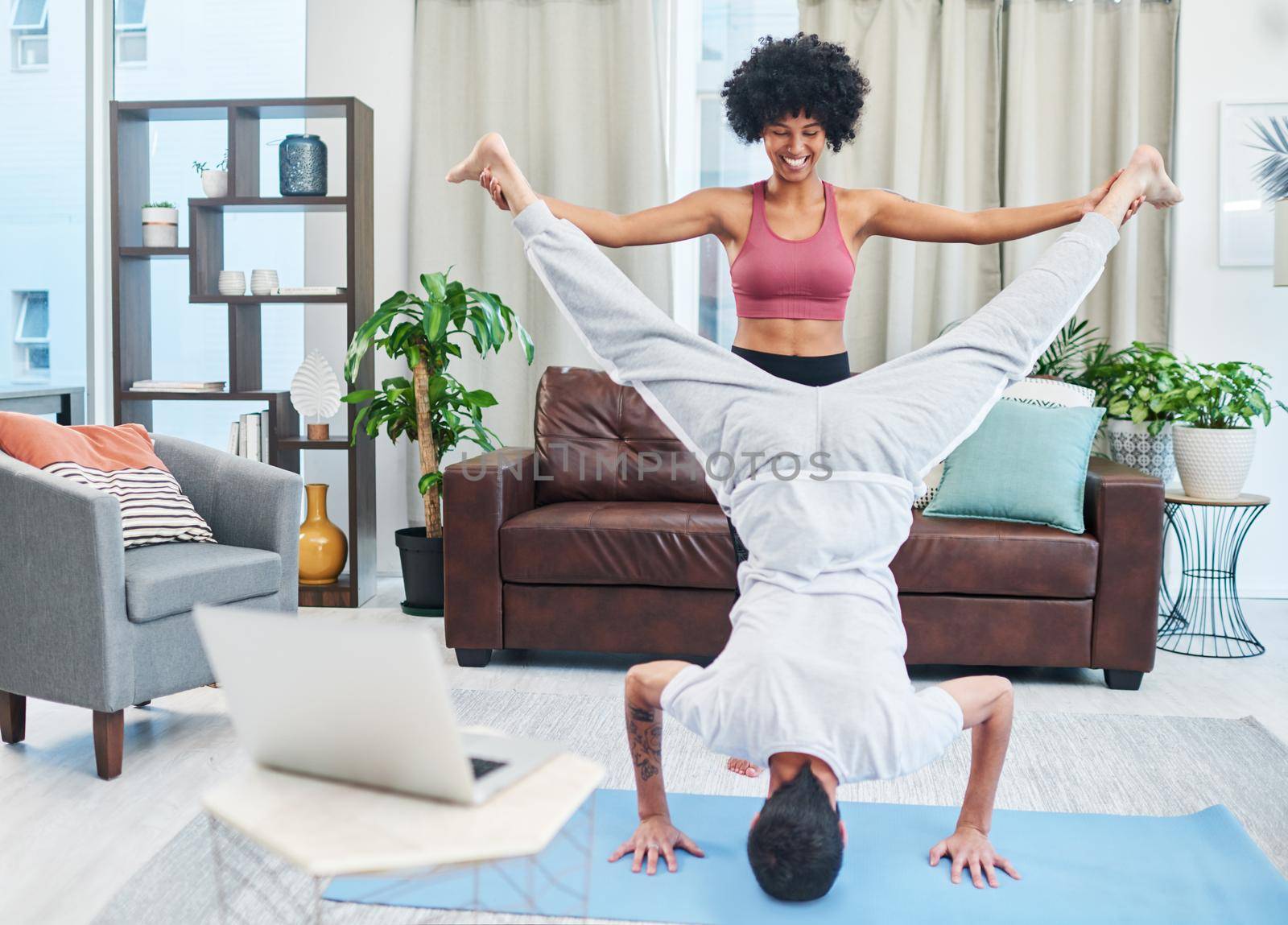 Couples Yoga is so much fun. a young couple practising yoga in their living room. by YuriArcurs