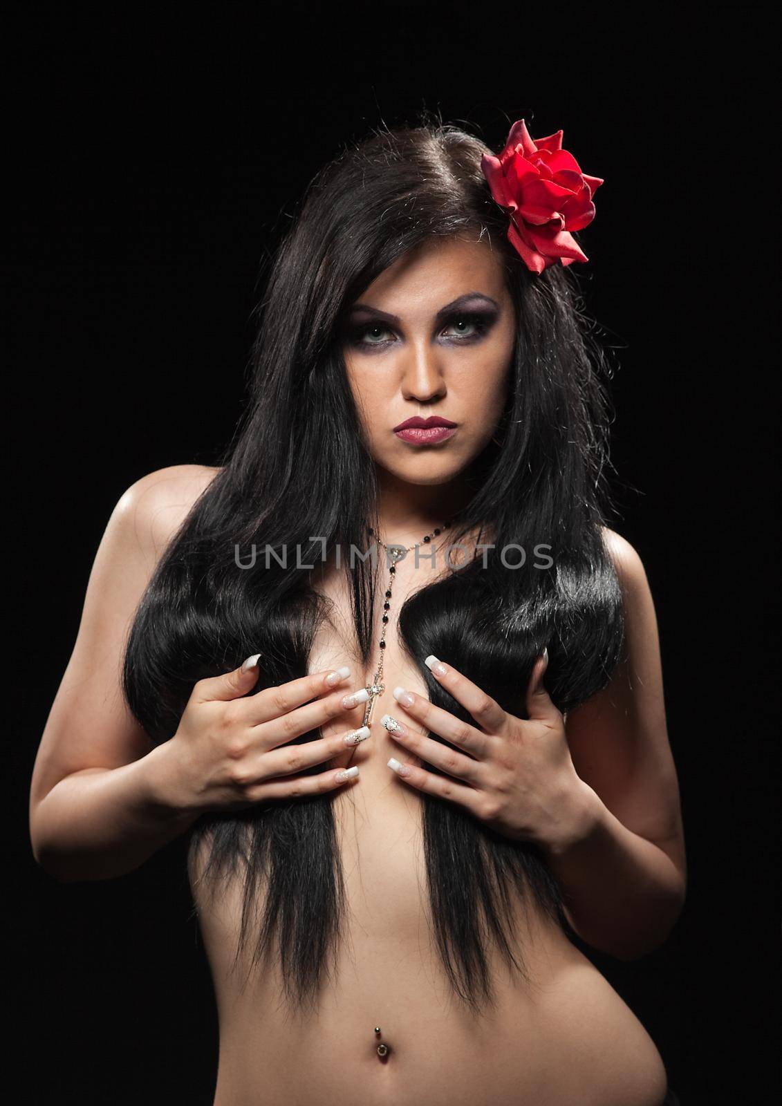 Woman with rose in dark hair take breast in hands