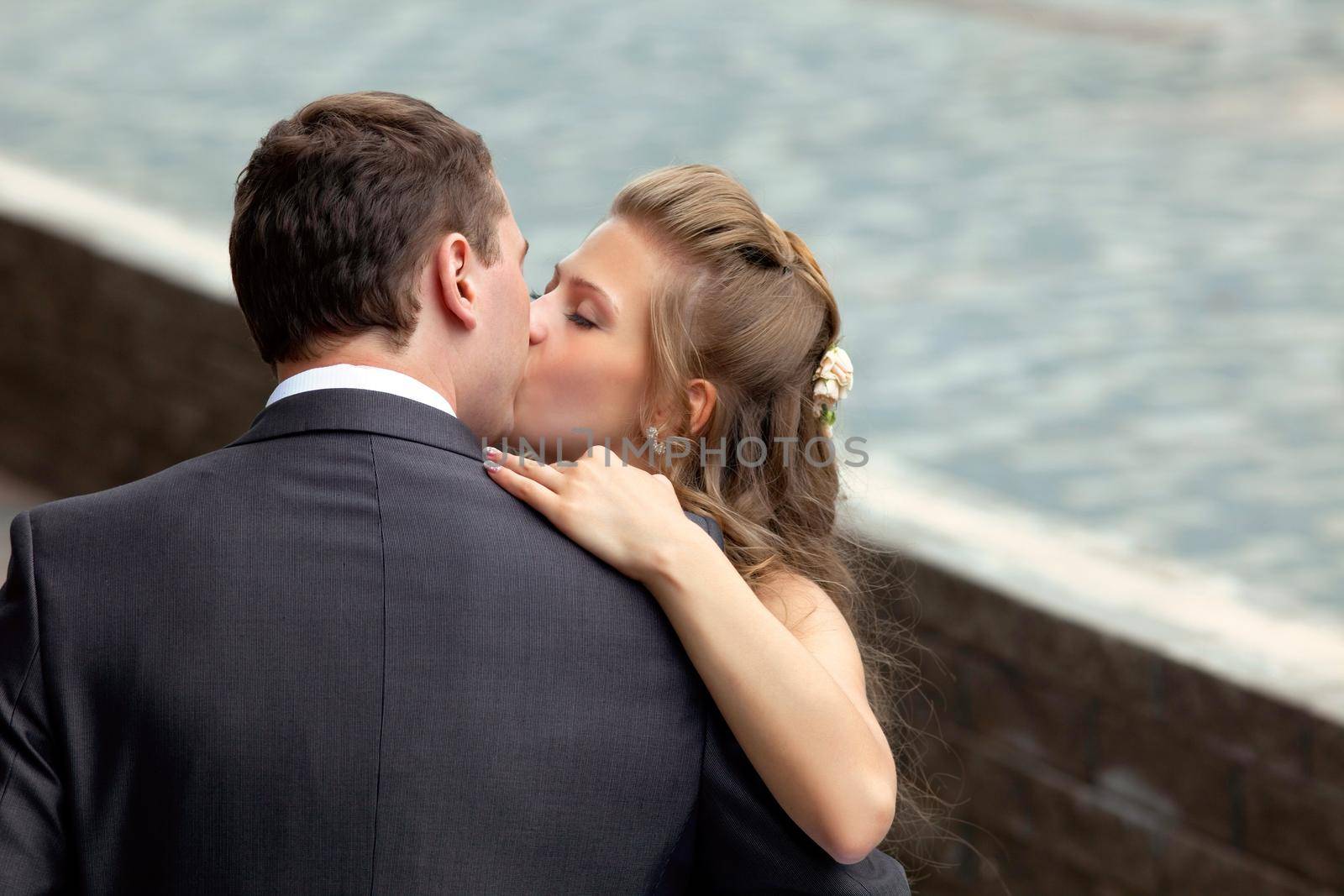 young wedding couple kissing by rivertime
