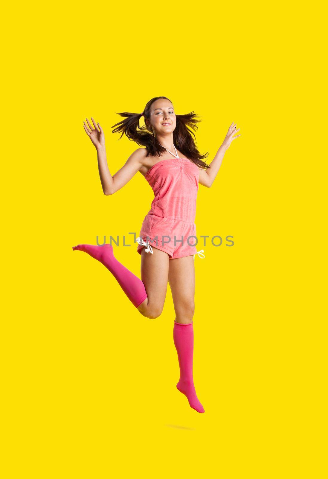 Beauty playful woman like girl jump on yellow