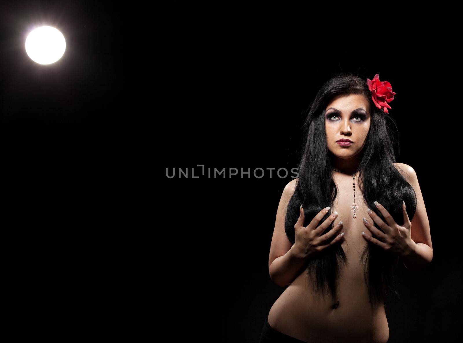 Woman with rose in dark hair take breast in hands