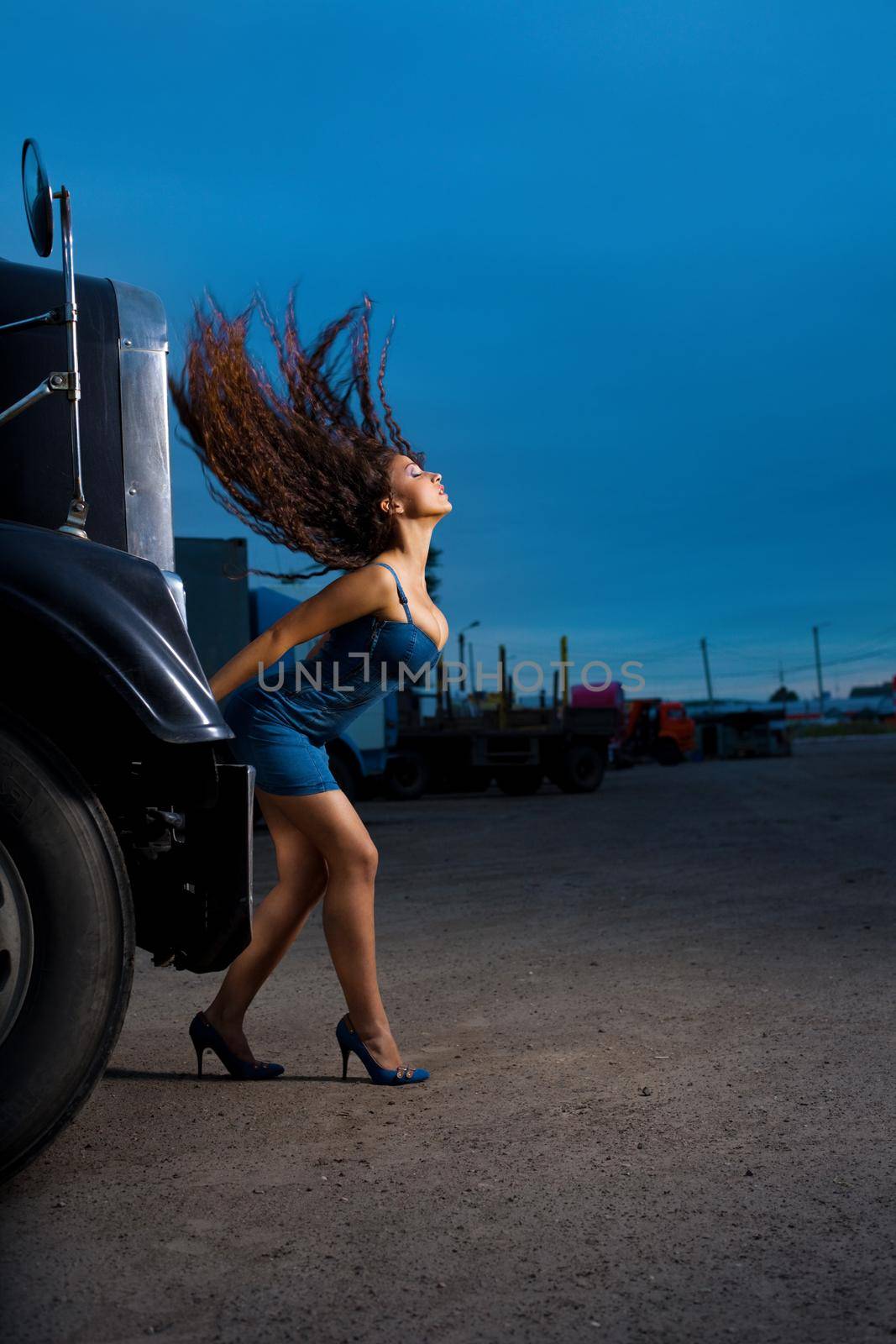 Young beauty girl posing near steel truck with long hair at night
