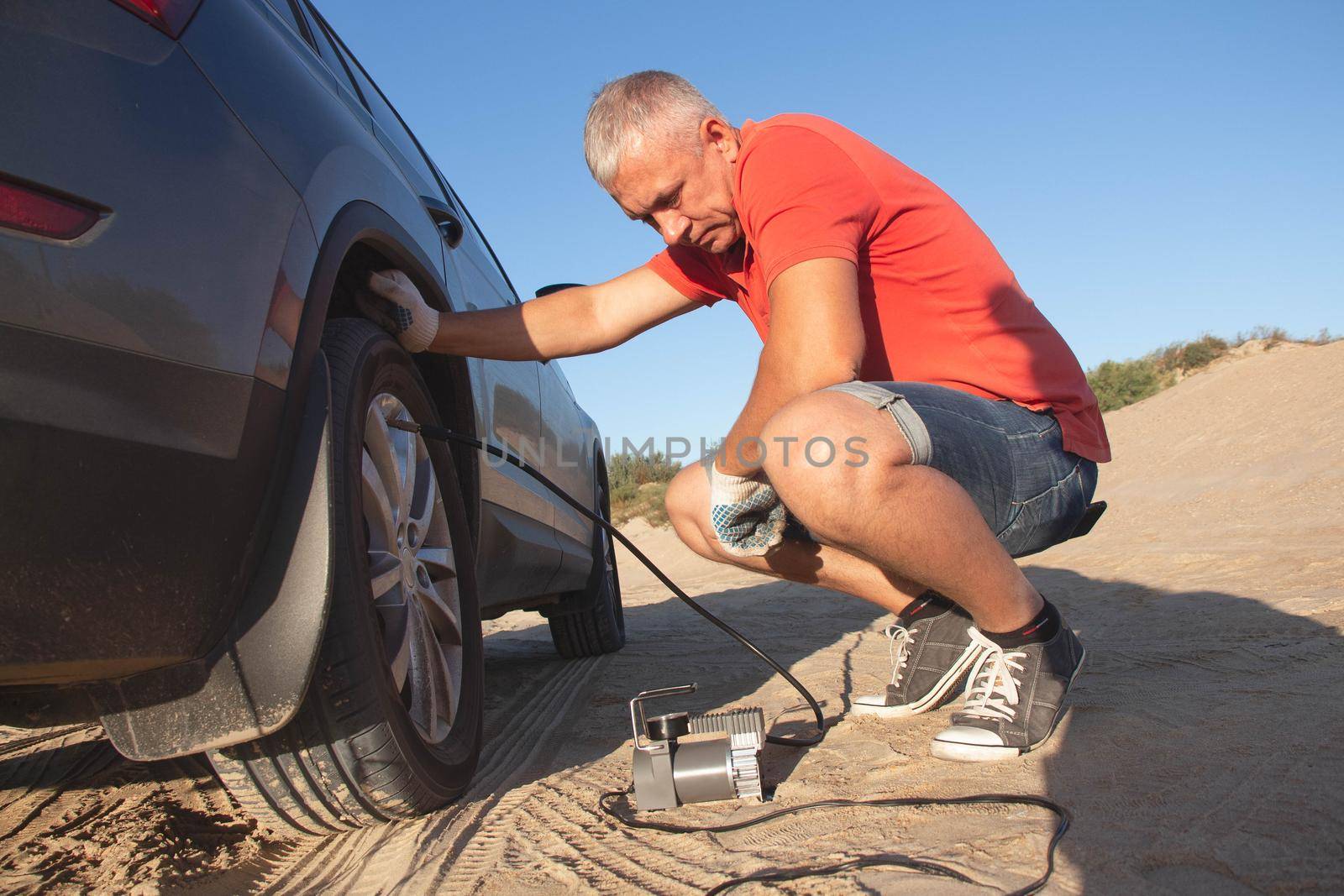 A man checks tire pressure. Travel to the sea by car.