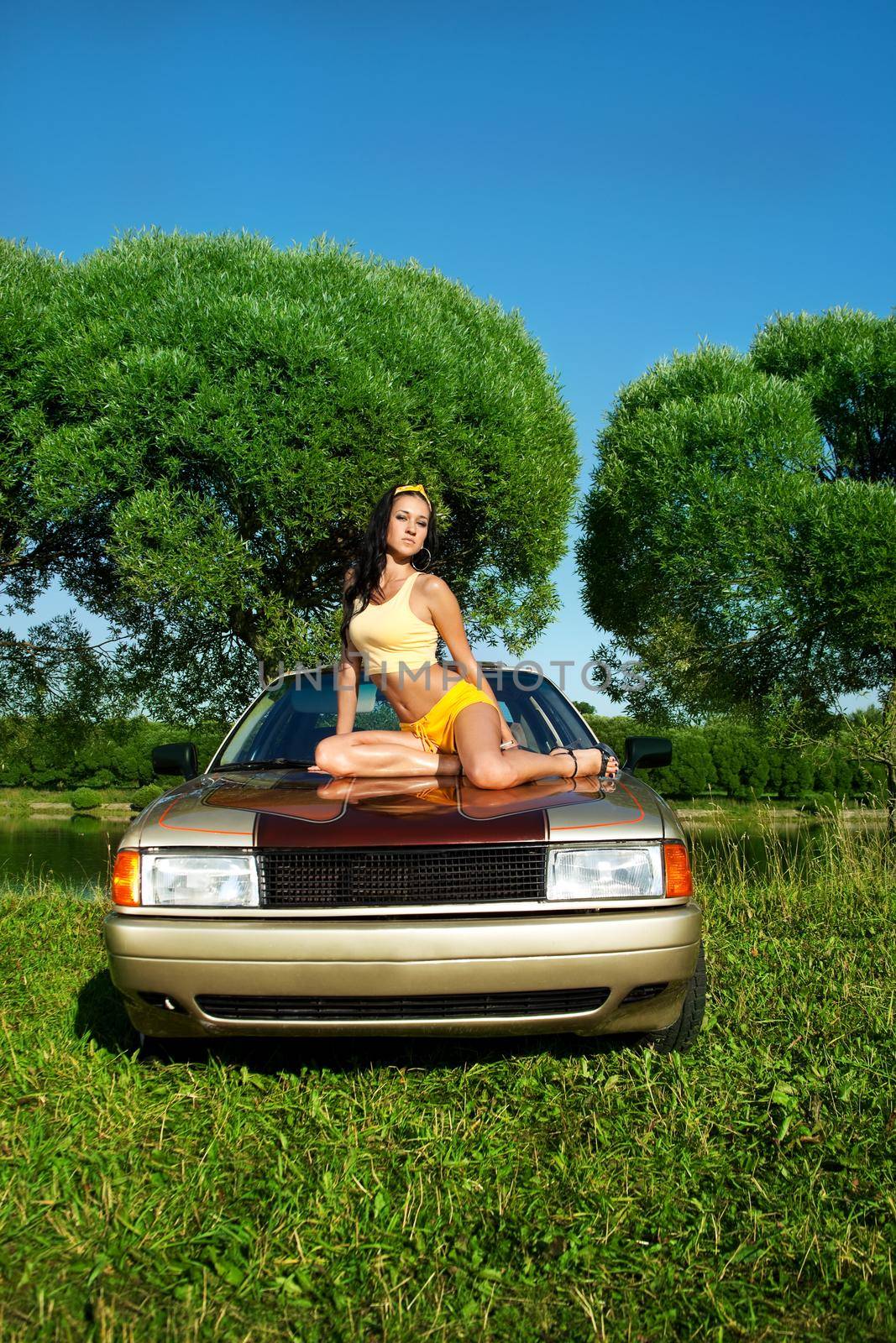 Sexy young girl sit on retro car at summer sunset