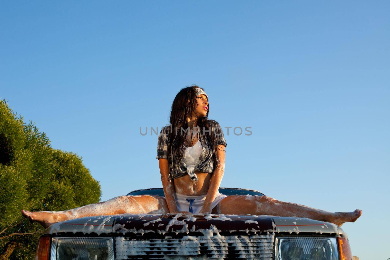sexy young girl washing a car at summer sunset
