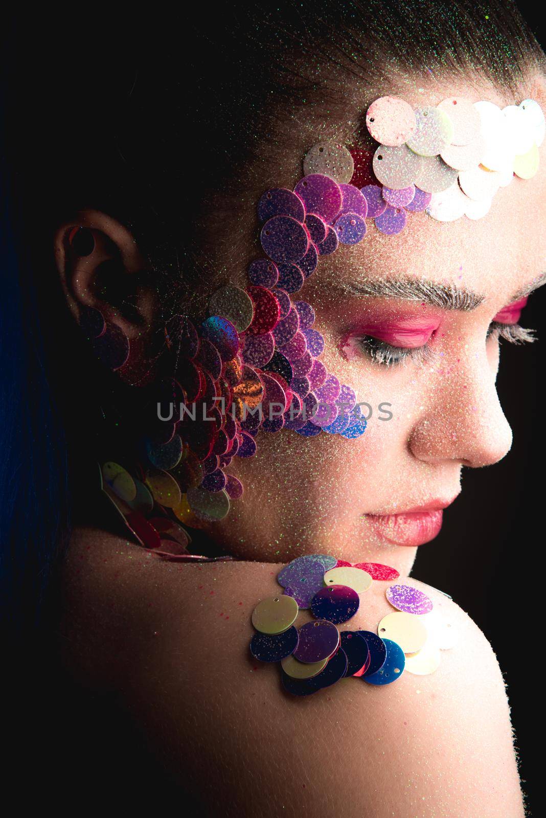 Creative sandy face makeup of a girl with colorful sequins