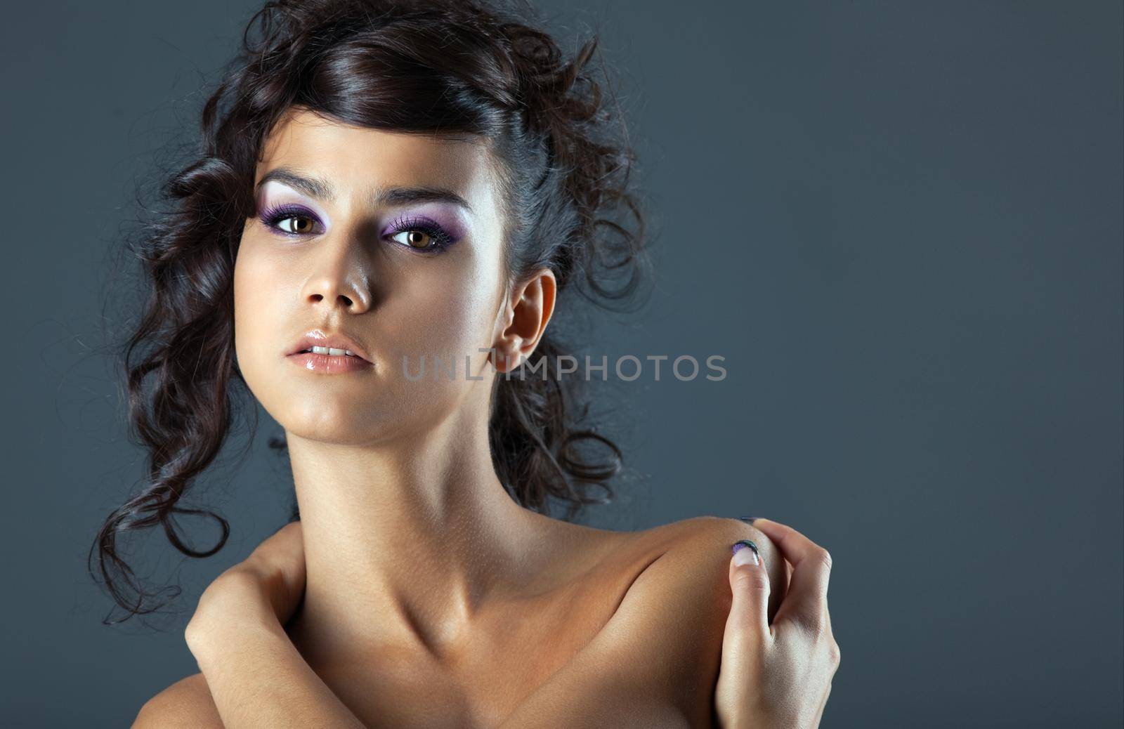 Attractive young brunette woman close-up portrait on grey