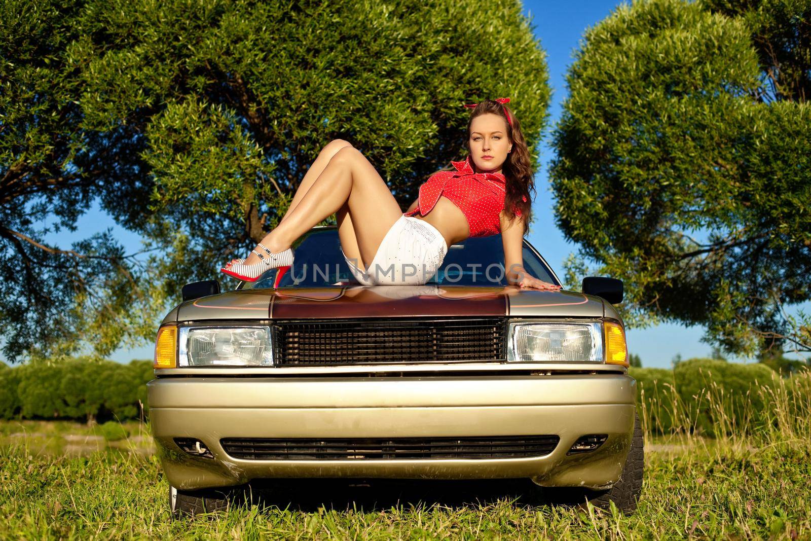 young sexy woman lay on car bonnet by rivertime