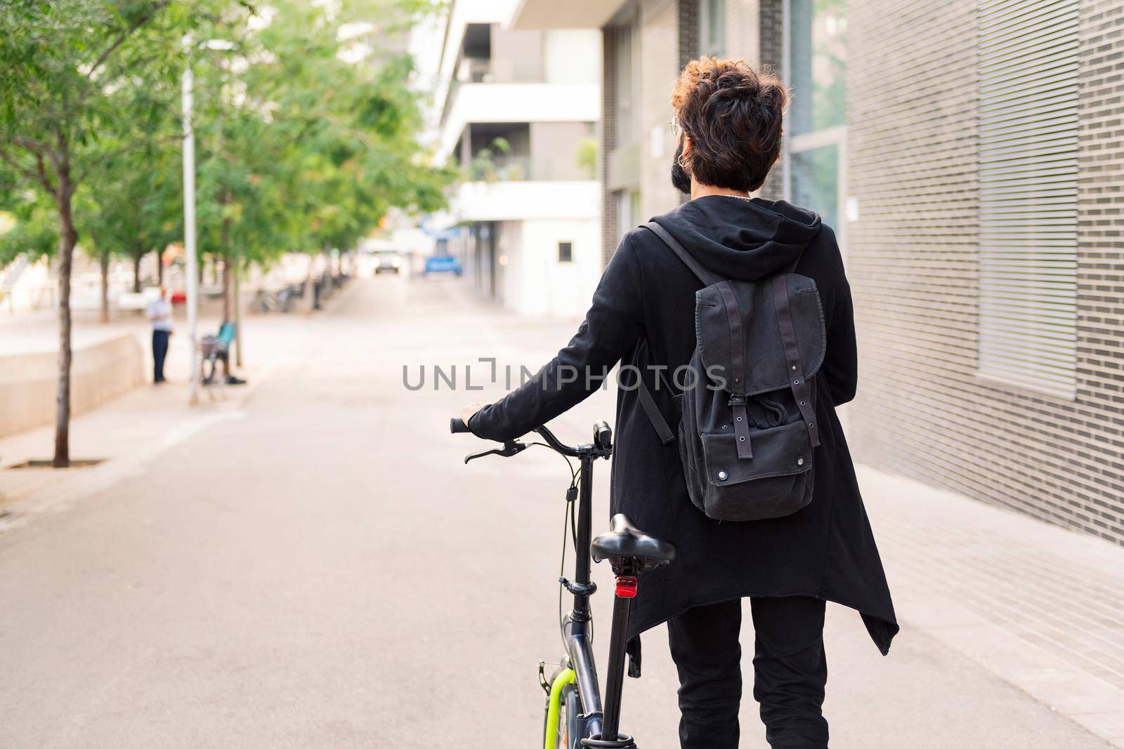rear view of an unrecognizable young man walking with his bike, concept of urban lifestyle and sustainable mobility, copy space for text