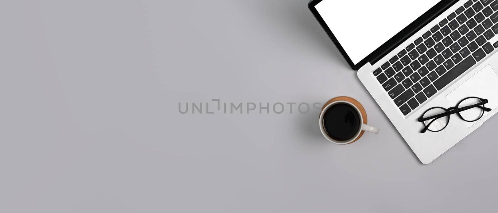 Flat lay laptop with empty display, eyeglasses and coffee cup on white background. Copy space for your text.
