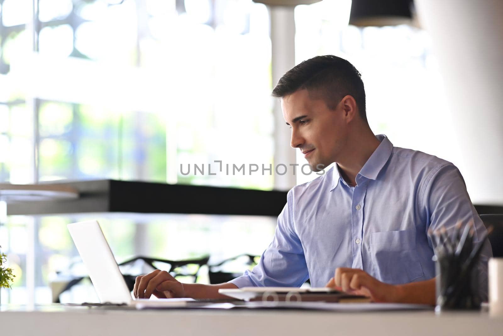 Confident businessman checking email with laptop computer at his office room.