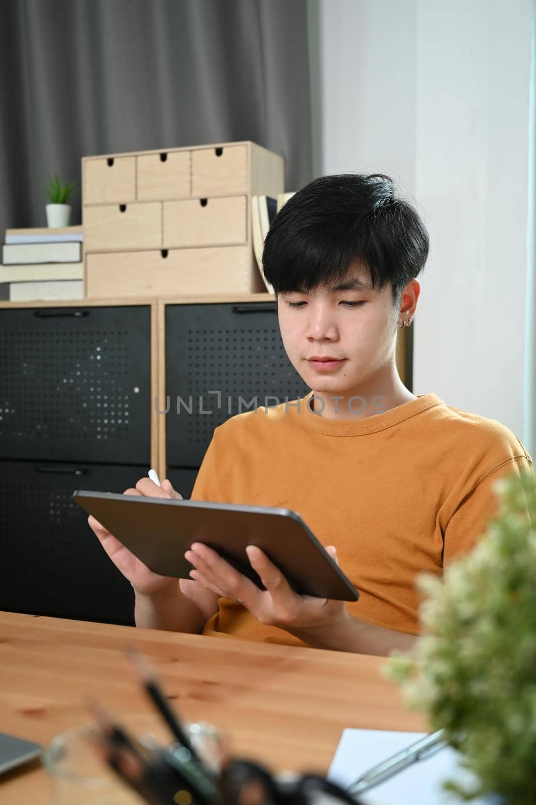 Young man in casual clothes using digital tablet at home.