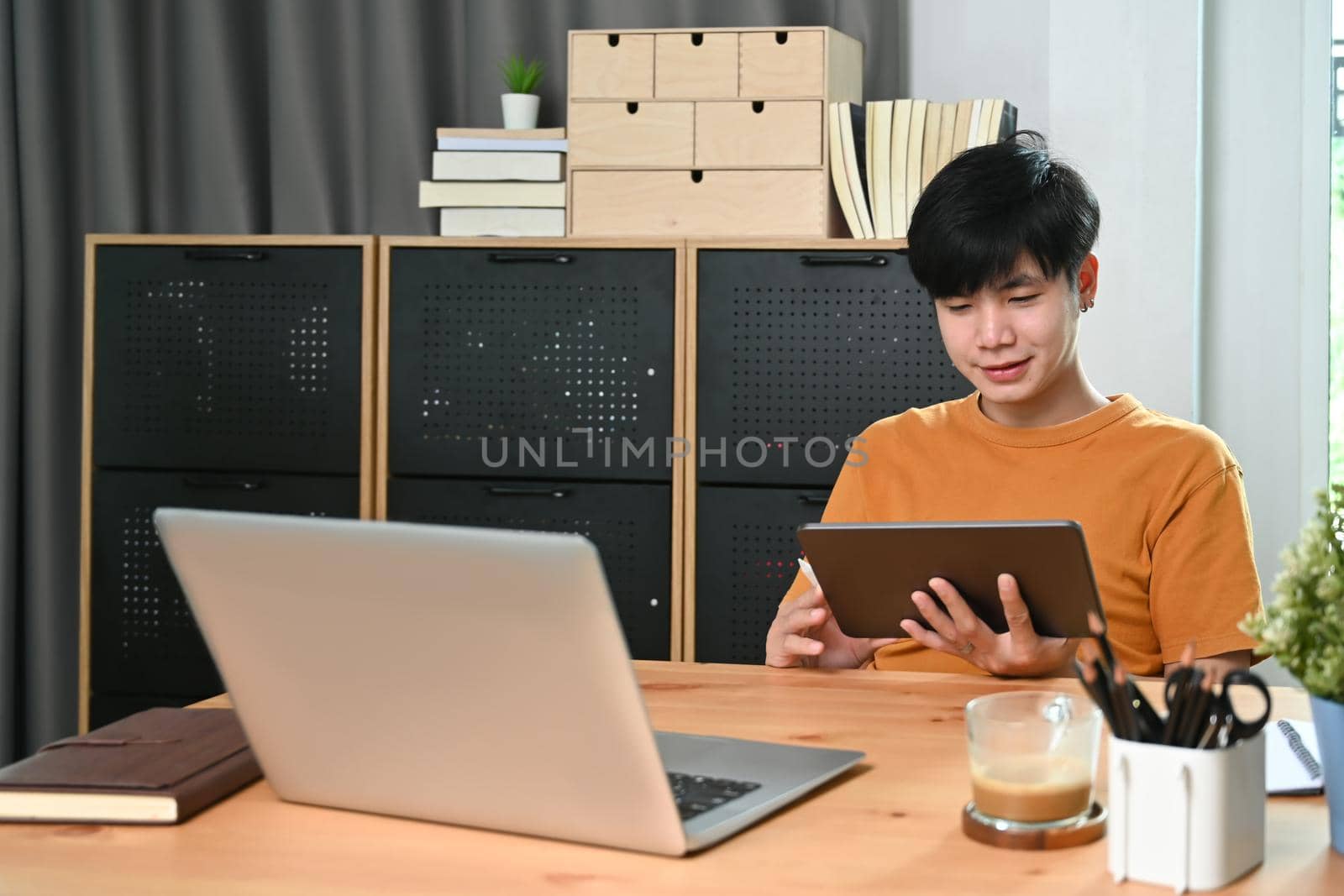 Happy asian man using digital tablet at home.